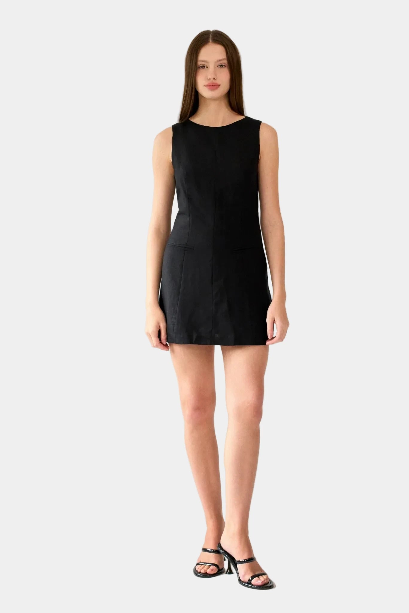 Modelo usando vestido curto preto sem mangas com modelagem reta