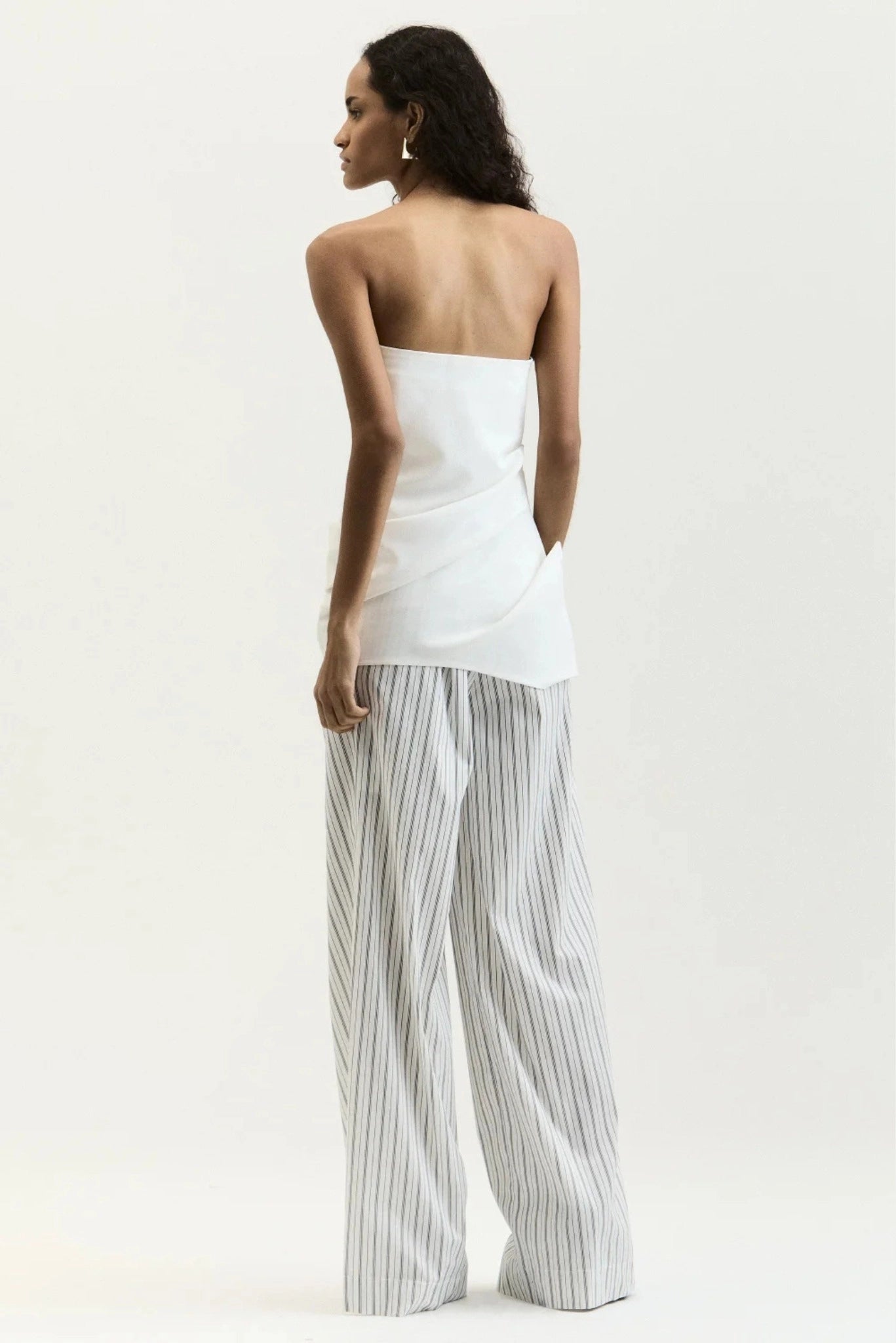 Costas da blusa branca tomara que caia com detalhe drapeado na barra