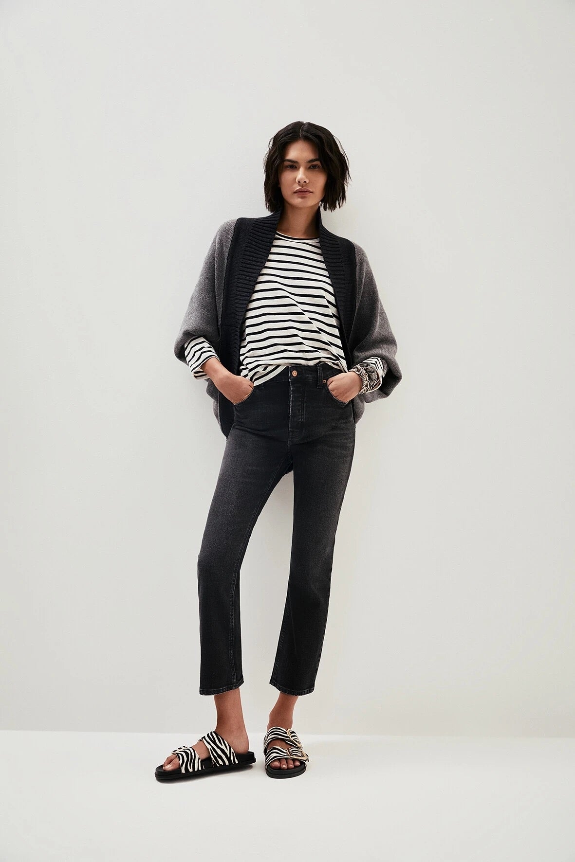 Modelo usando calça jeans preta cropped de cintura alta em look casual