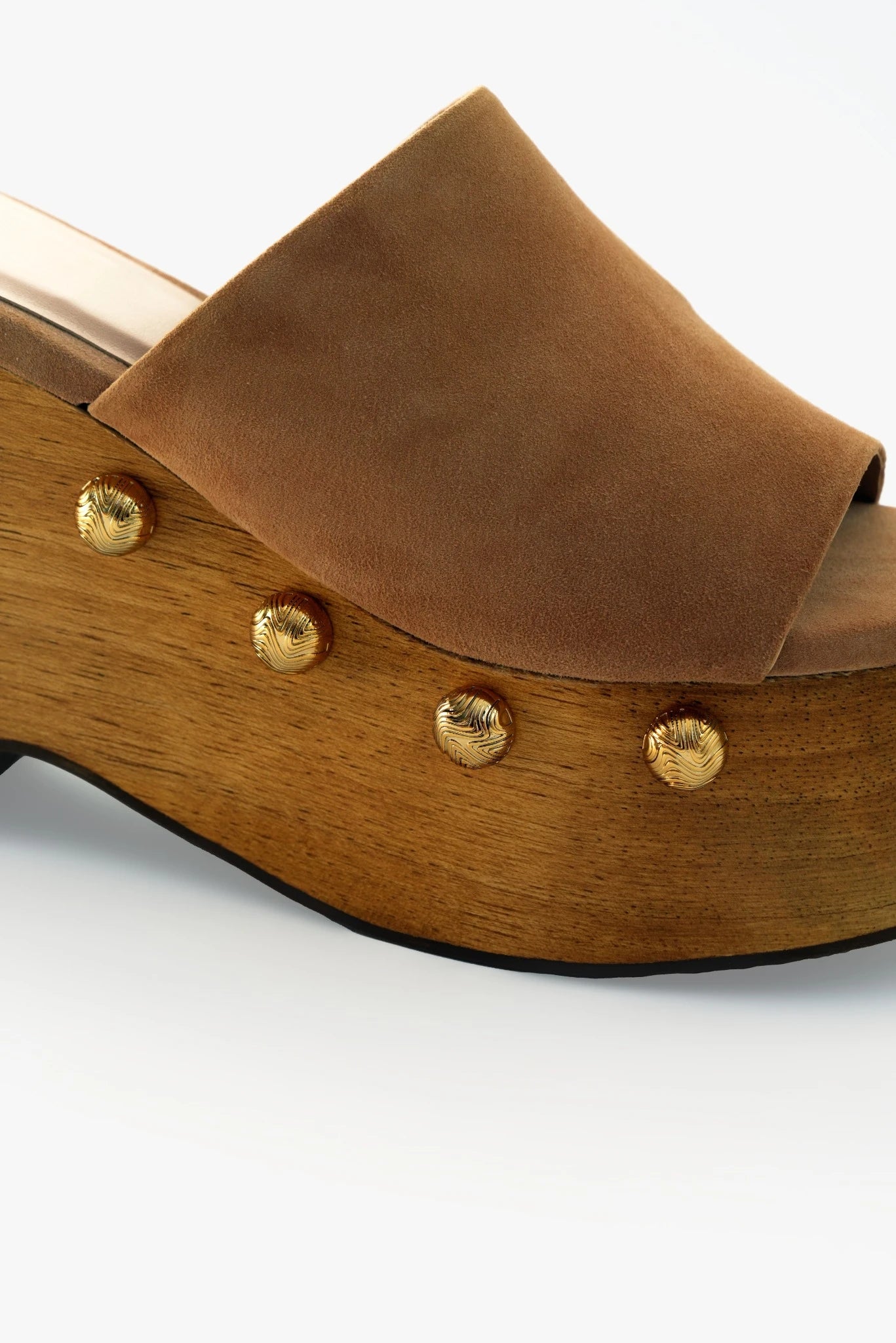 Close do clog Huda MR em camurça caramelo com tachas metálicas douradas e acabamento em madeira