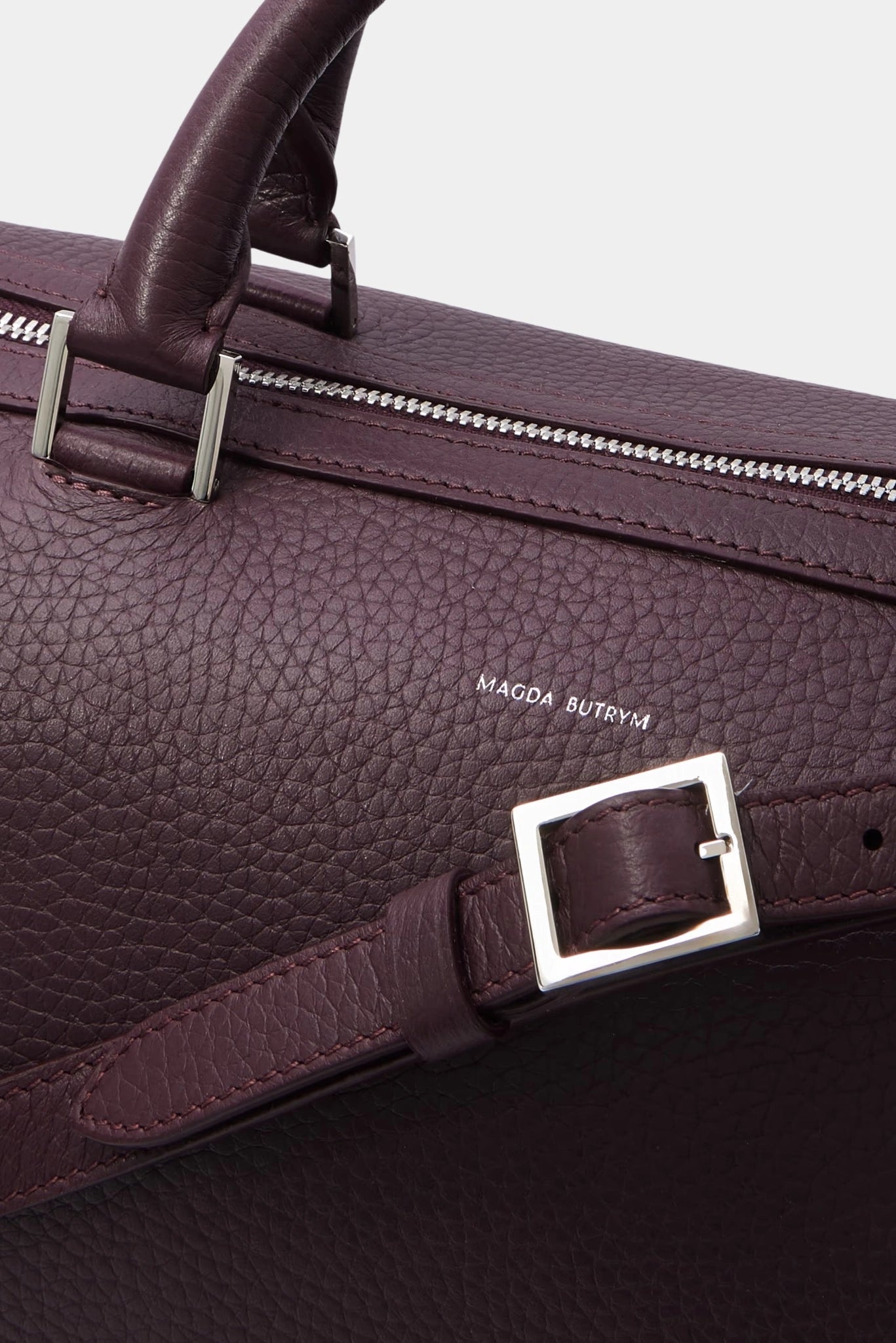 Close do acabamento da bolsa Magda Butrym em couro granulado com ferragens metálicas e logo discreto