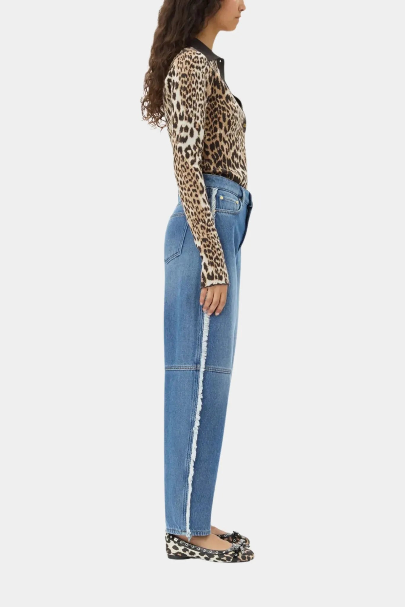 Vista lateral da calça jeans Ganni azul com acabamento desfiado e modelagem barrel