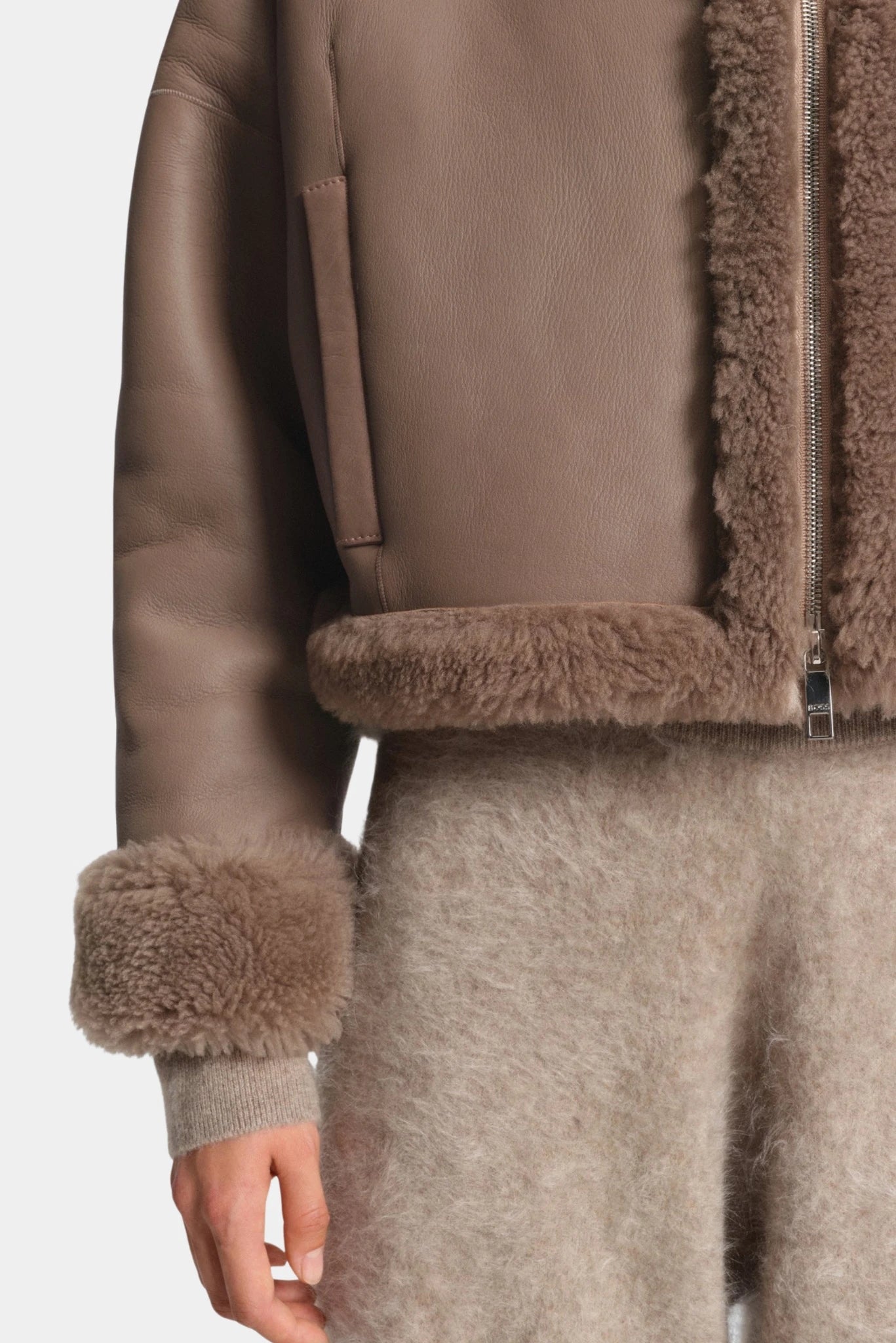 Detalhe da jaqueta double face marrom com acabamento shearling e bolso lateral