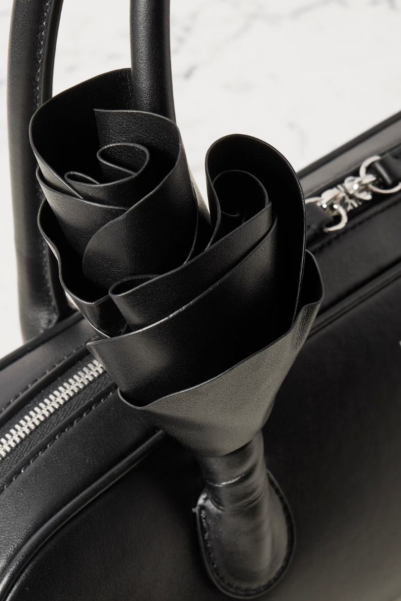 Detalhe floral tridimensional em couro preto aplicado na alça da bolsa Brigitte