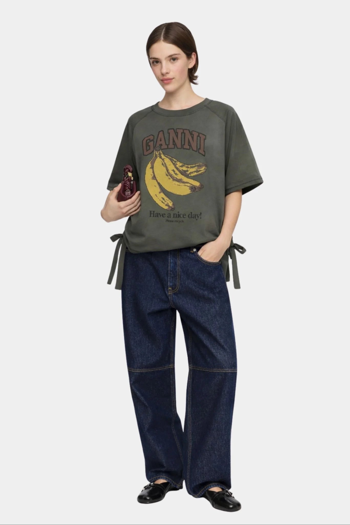 Modelo usando camiseta Ganni verde oliva com estampa de bananas e modelagem ampla