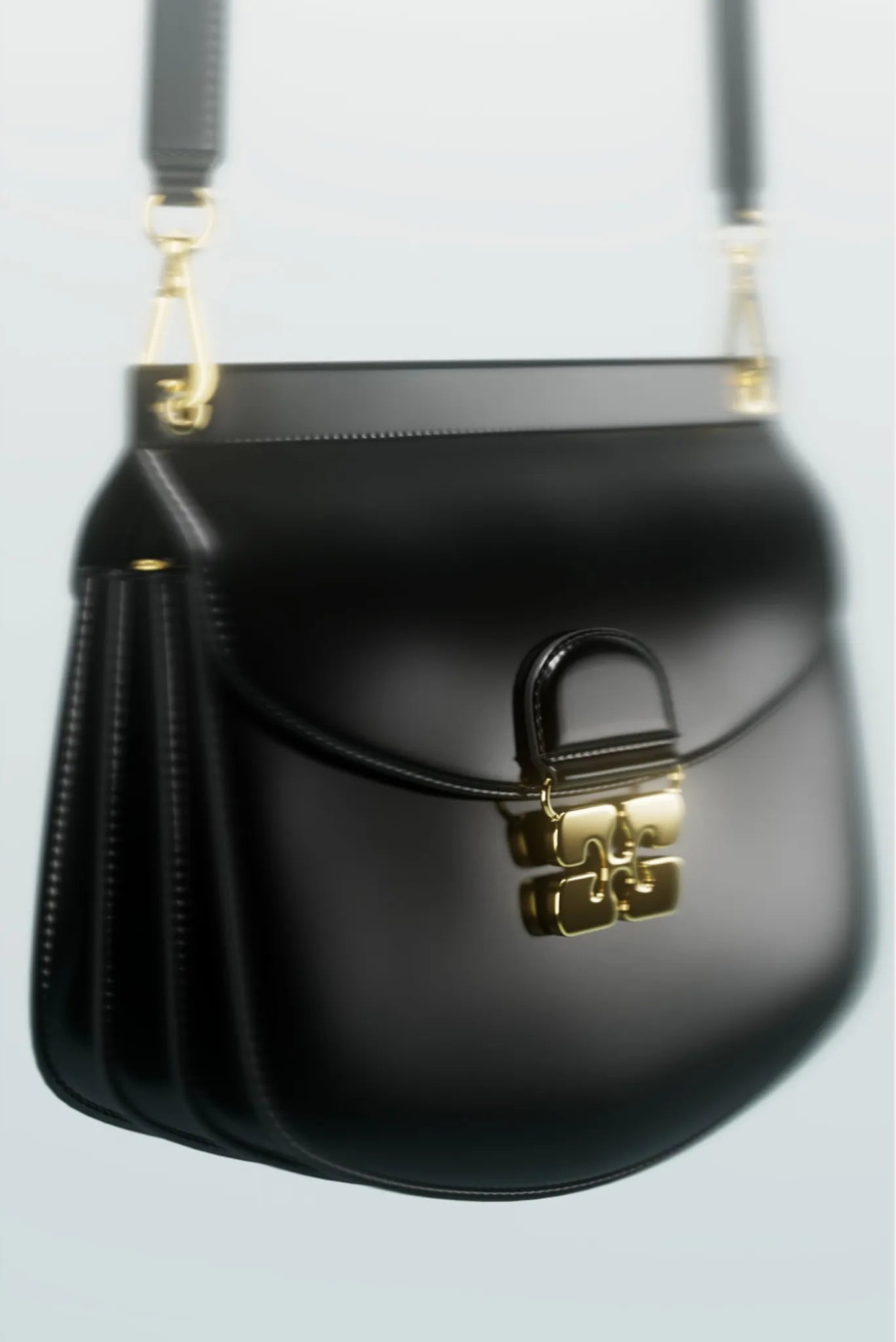 Detalhe da bolsa Ganni Apo-G preta com fecho metálico dourado e aba curva