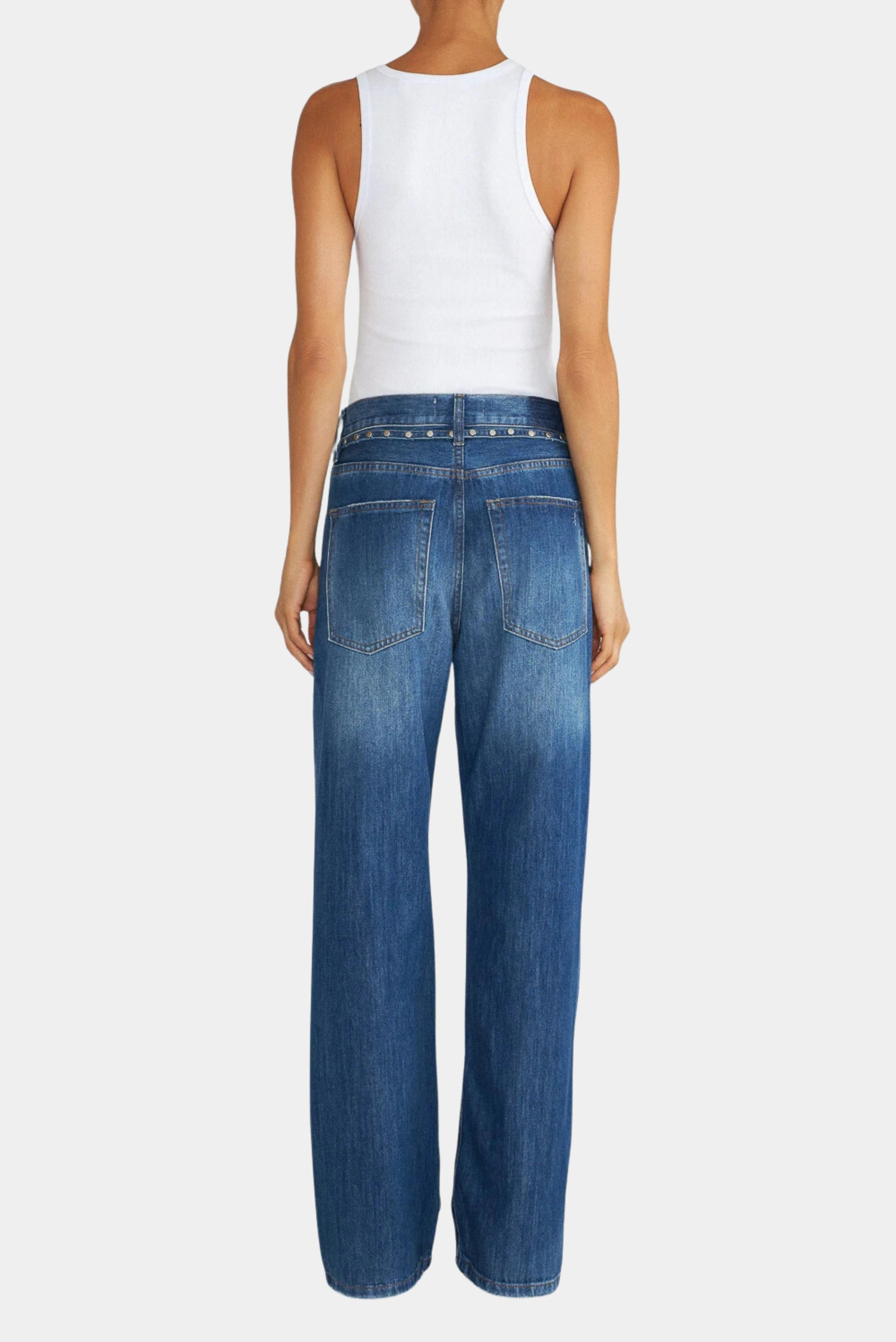 Vista traseira da calça jeans loose azul com bolsos posteriores e detalhe de faixa com tachas.