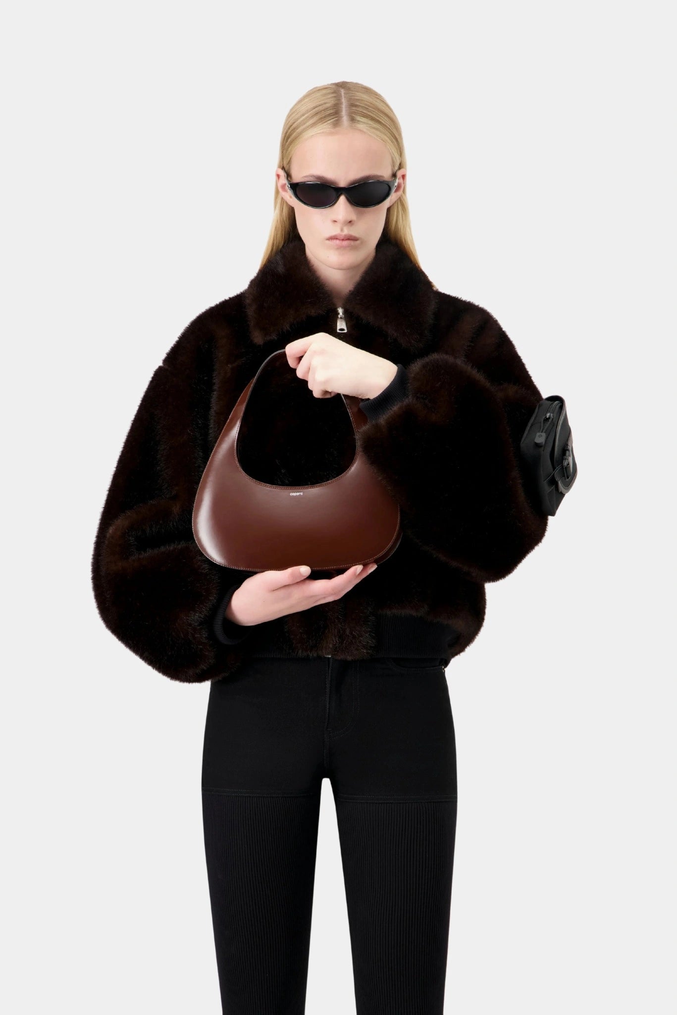 Modelo segurando bolsa marrom Coperni Slim Swipe em look monocromático