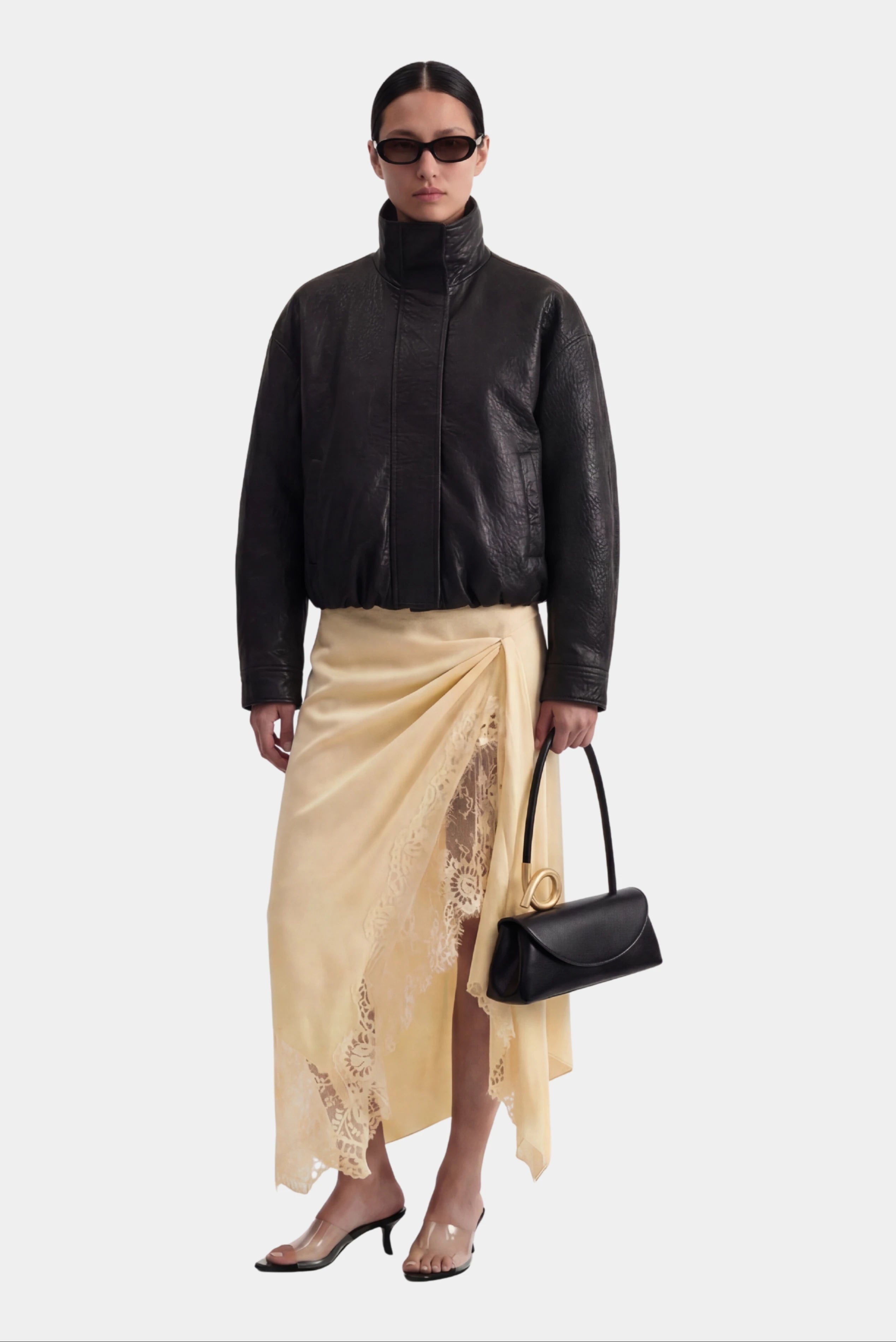 Jaqueta Philo MR de couro preta com gola alta em look feminino com saia midi acetinada