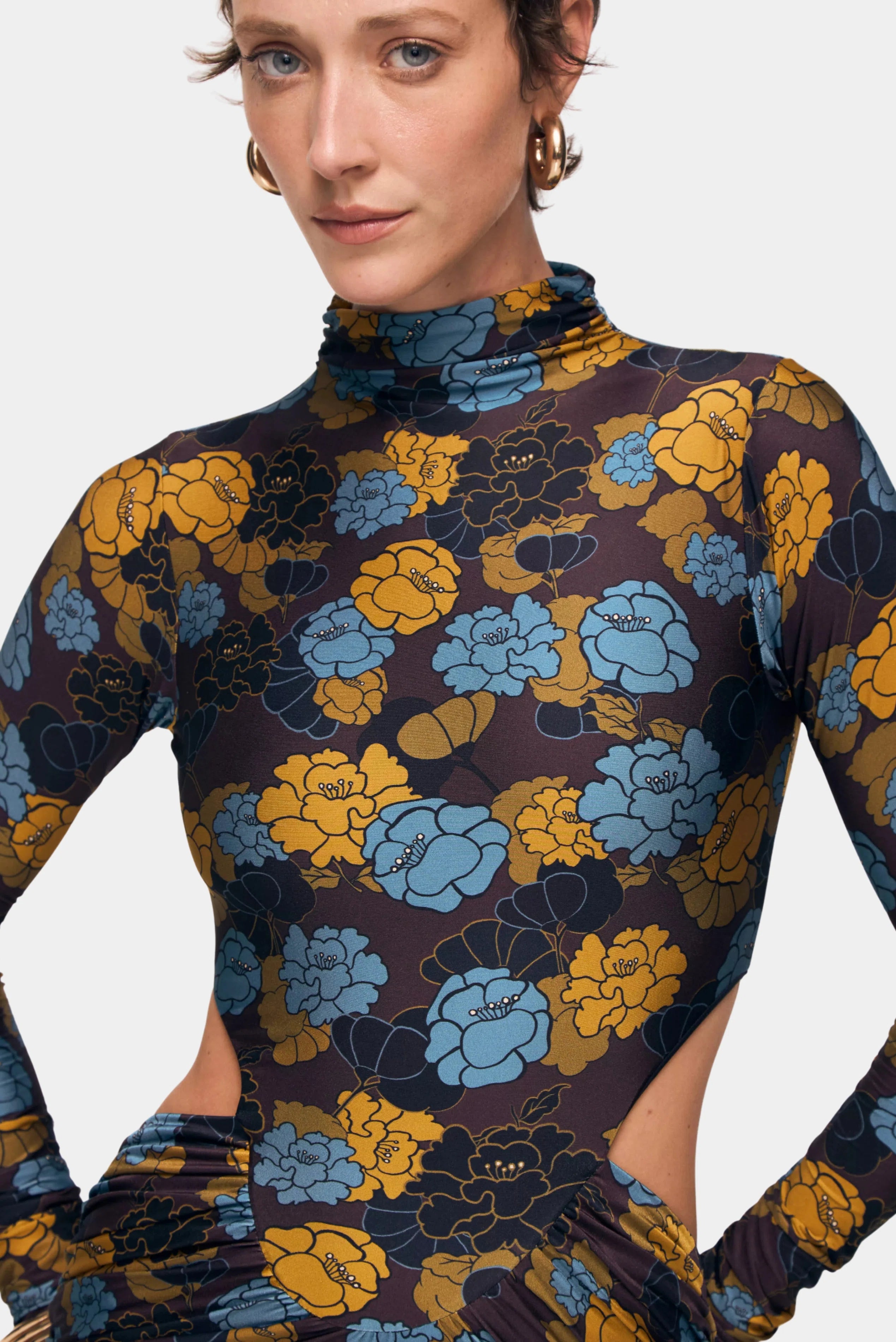 Detalhe da estampa floral azul e mostarda em vestido de mangas longas com gola alta