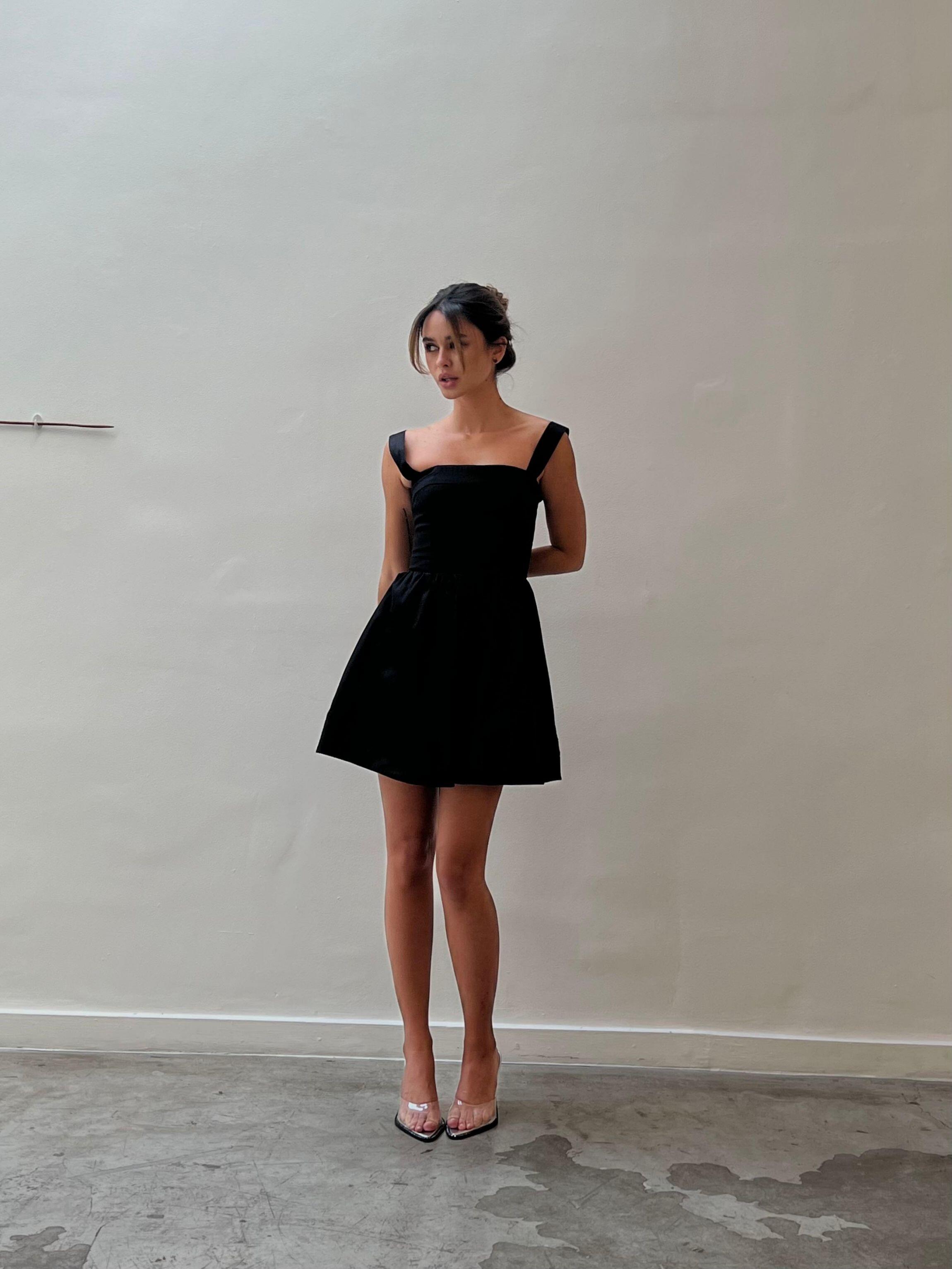 Modelo veste Vestido Curto Nico Gaia preto com decote reto e saia ampla