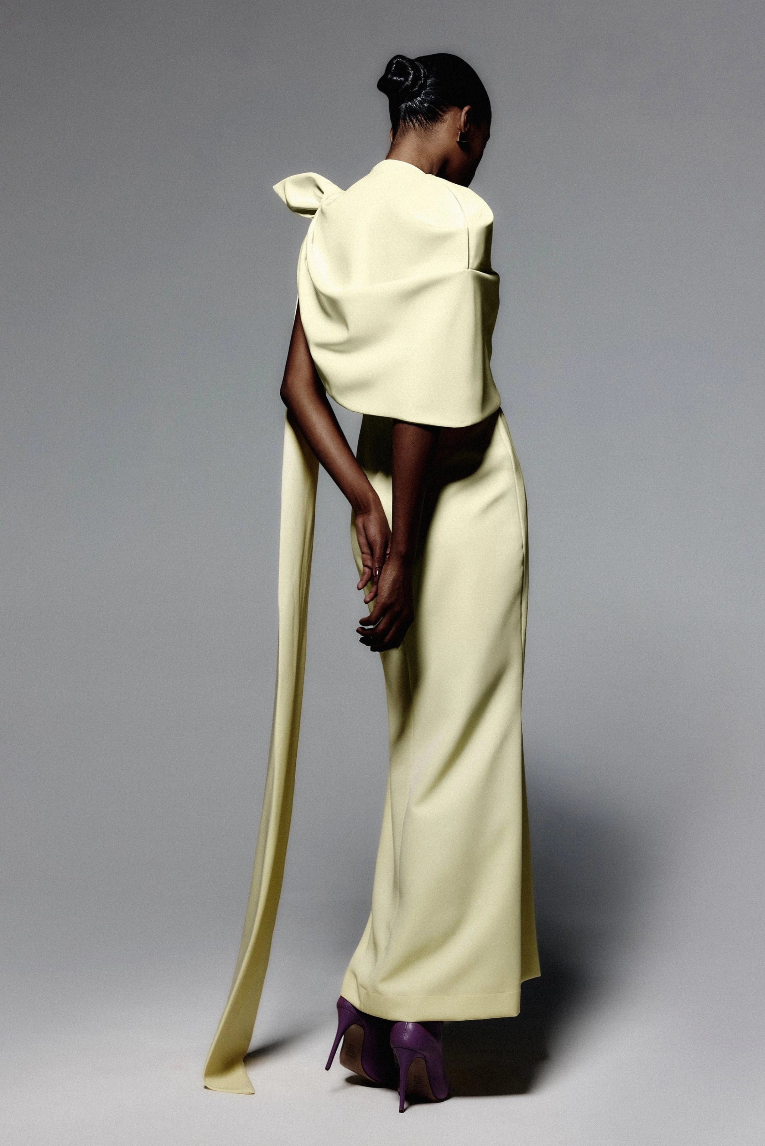 Vestido de festa amarelo-claro com capa ampla e detalhe alongado nas costas