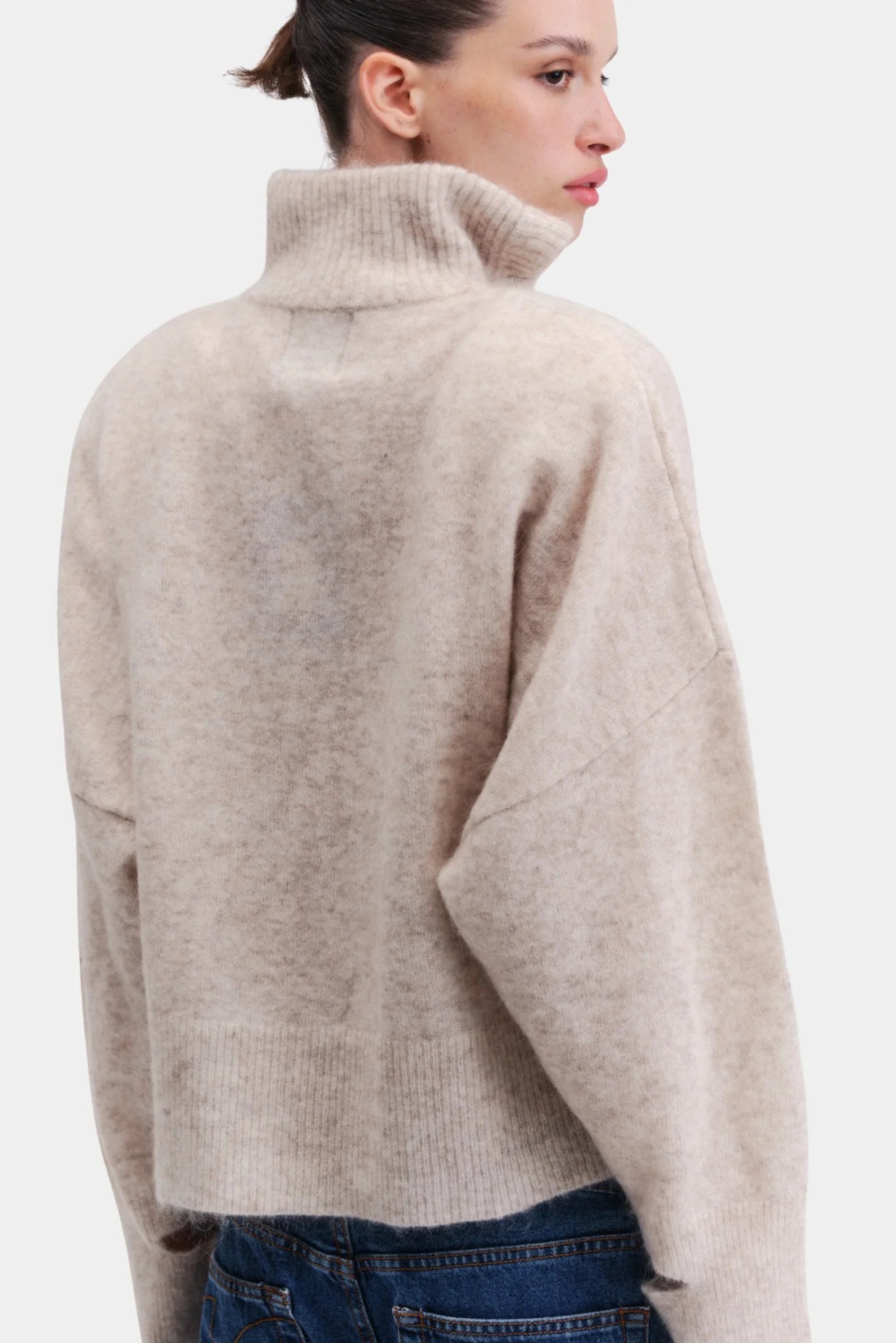 Costas do pullover oversized em tricot bege com gola alta e caimento amplo