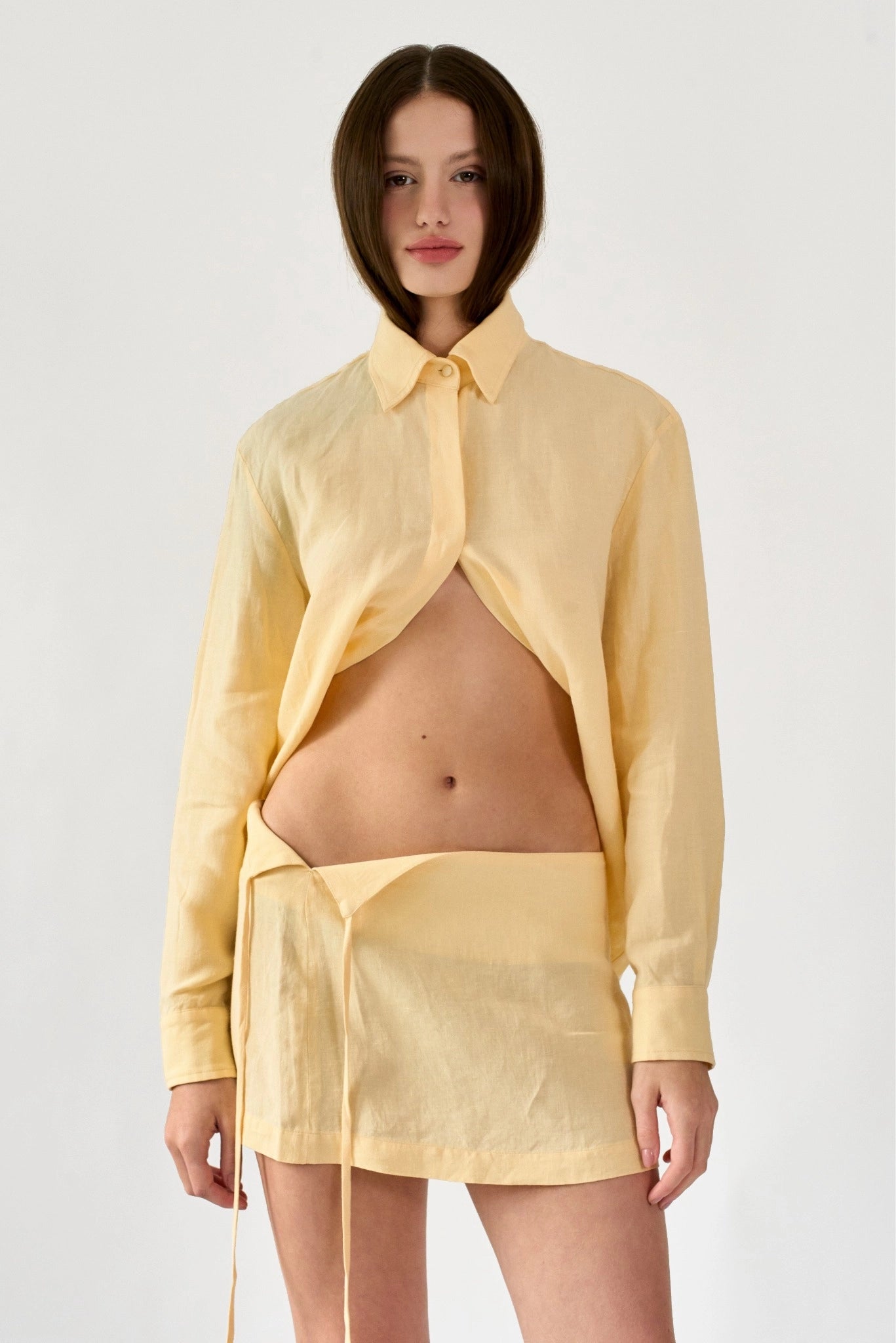 Modelo usando saia curta em linho amarelo claro com transpasse e amarração lateral