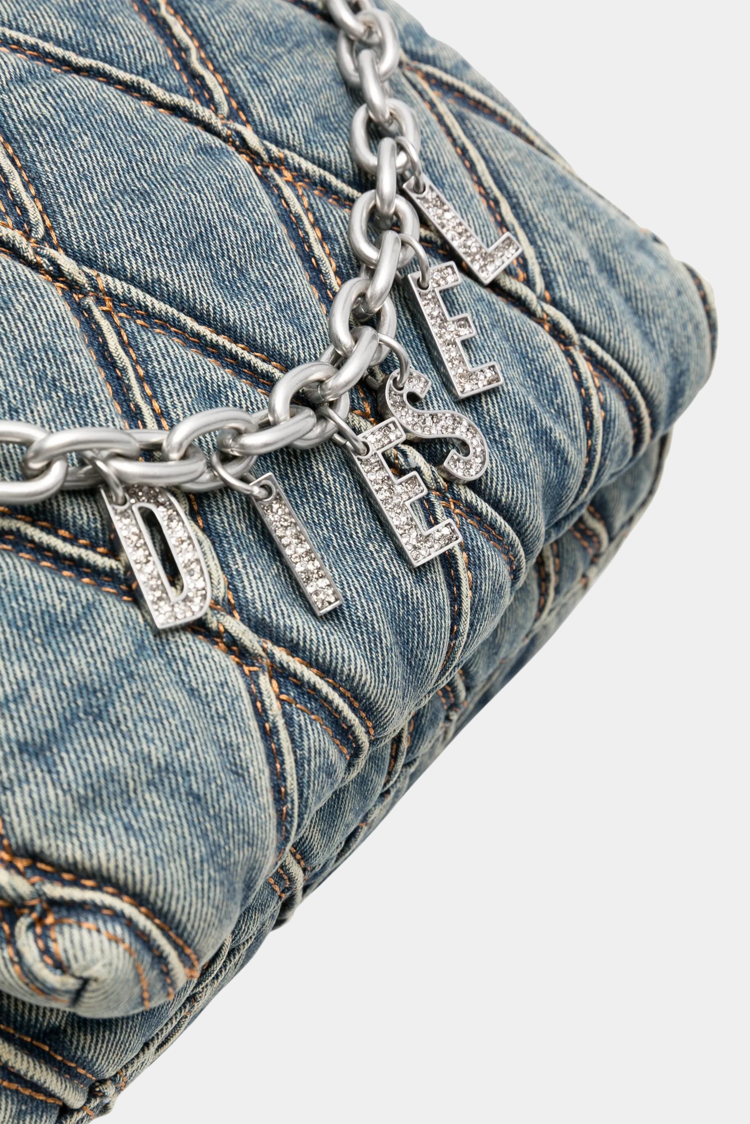 Detalhe de corrente metálica com pingentes Diesel em bolsa jeans matelassada