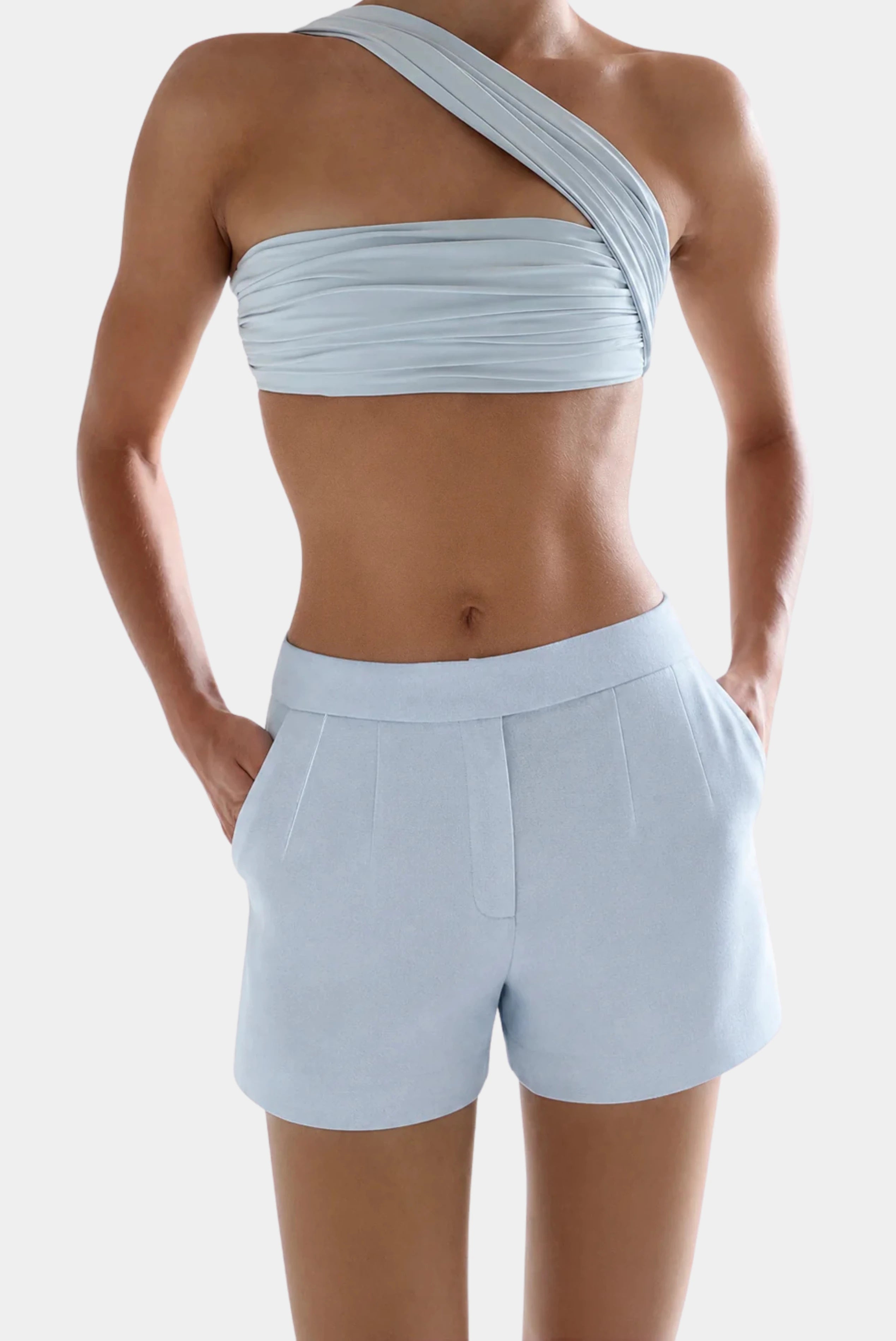 Top reto azul-claro com alça assimétrica drapeada combinado com short de alfaiataria.