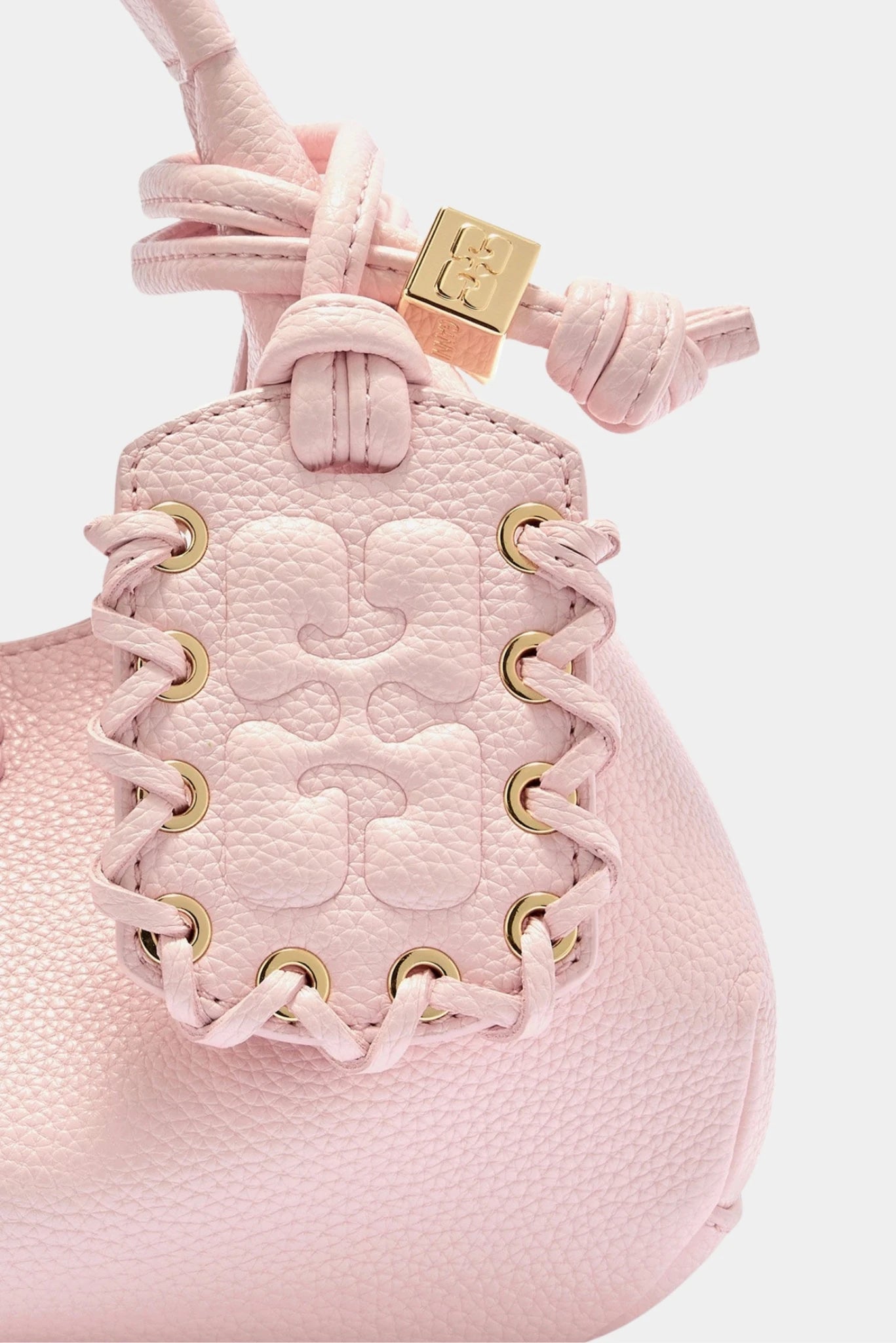 Detalhe trançado da bolsa Ganni Hobo Mini rosa com ilhós e ferragens douradas