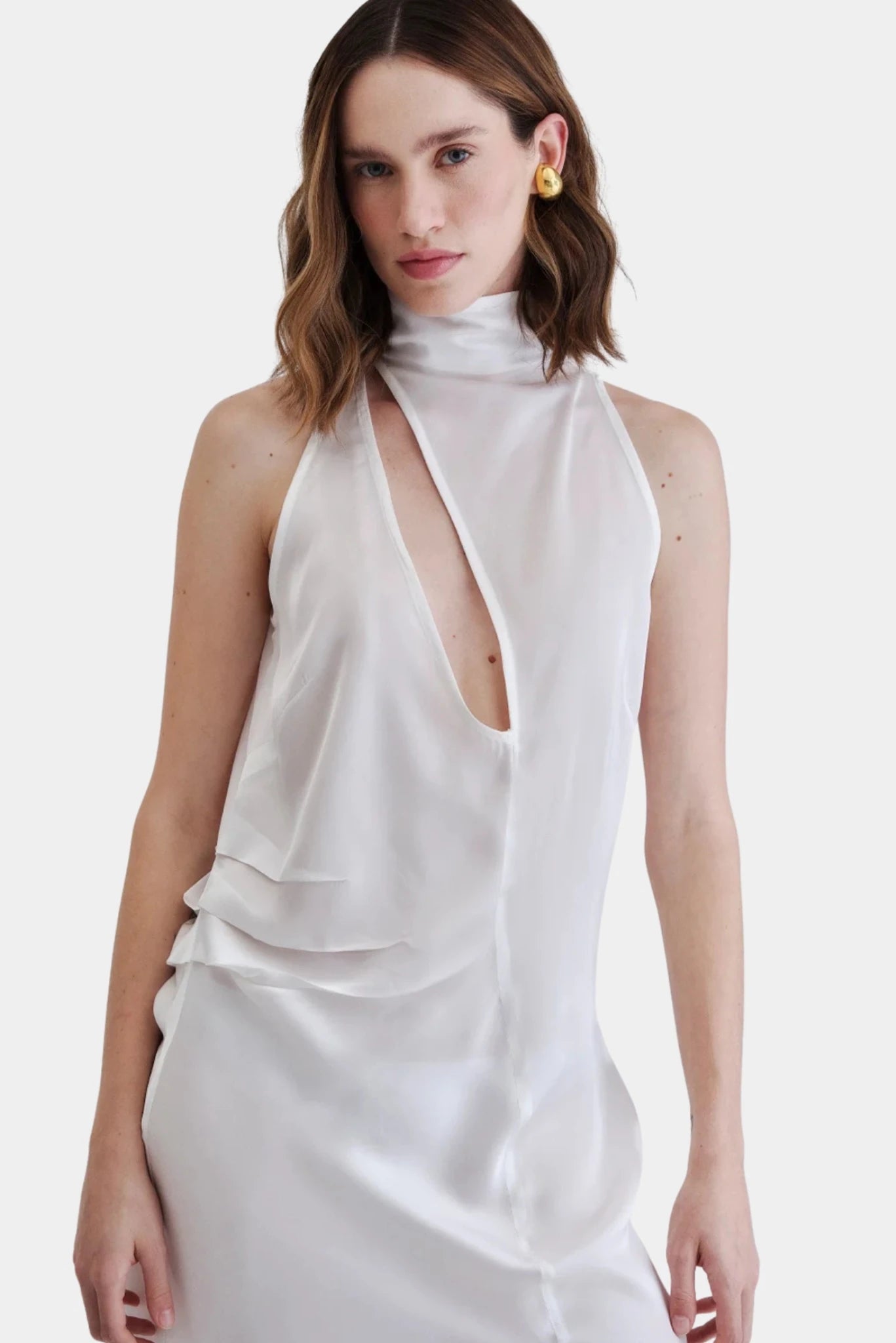 Detalhe do vestido branco com gola alta, decote profundo e recortes drapeados