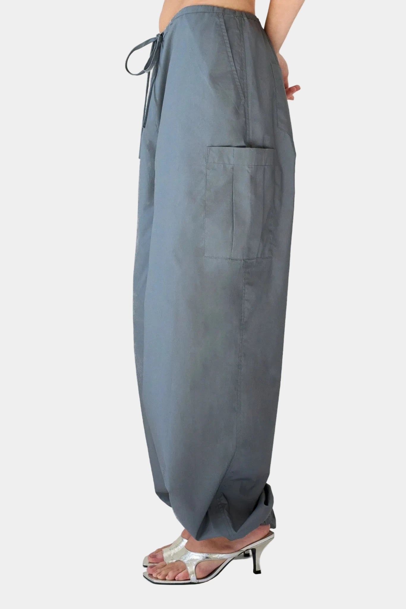 Vista lateral da calça balloon cargo Aya Gaia cinza com bolso utilitário aplicado