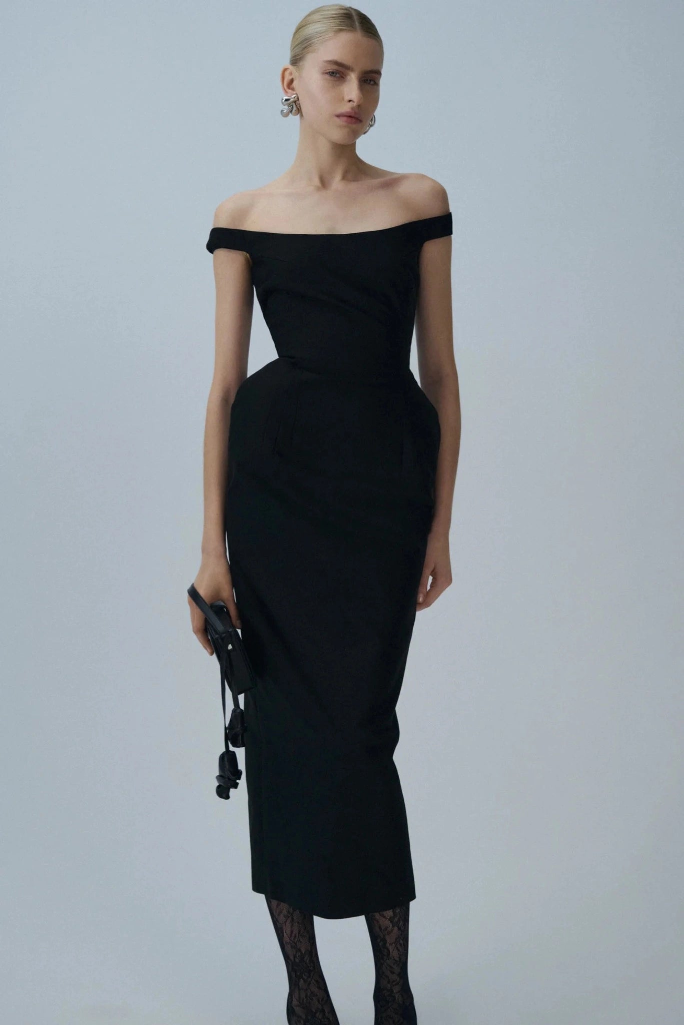 Modelo usando vestido midi preto Magda Butrym com decote ombro a ombro