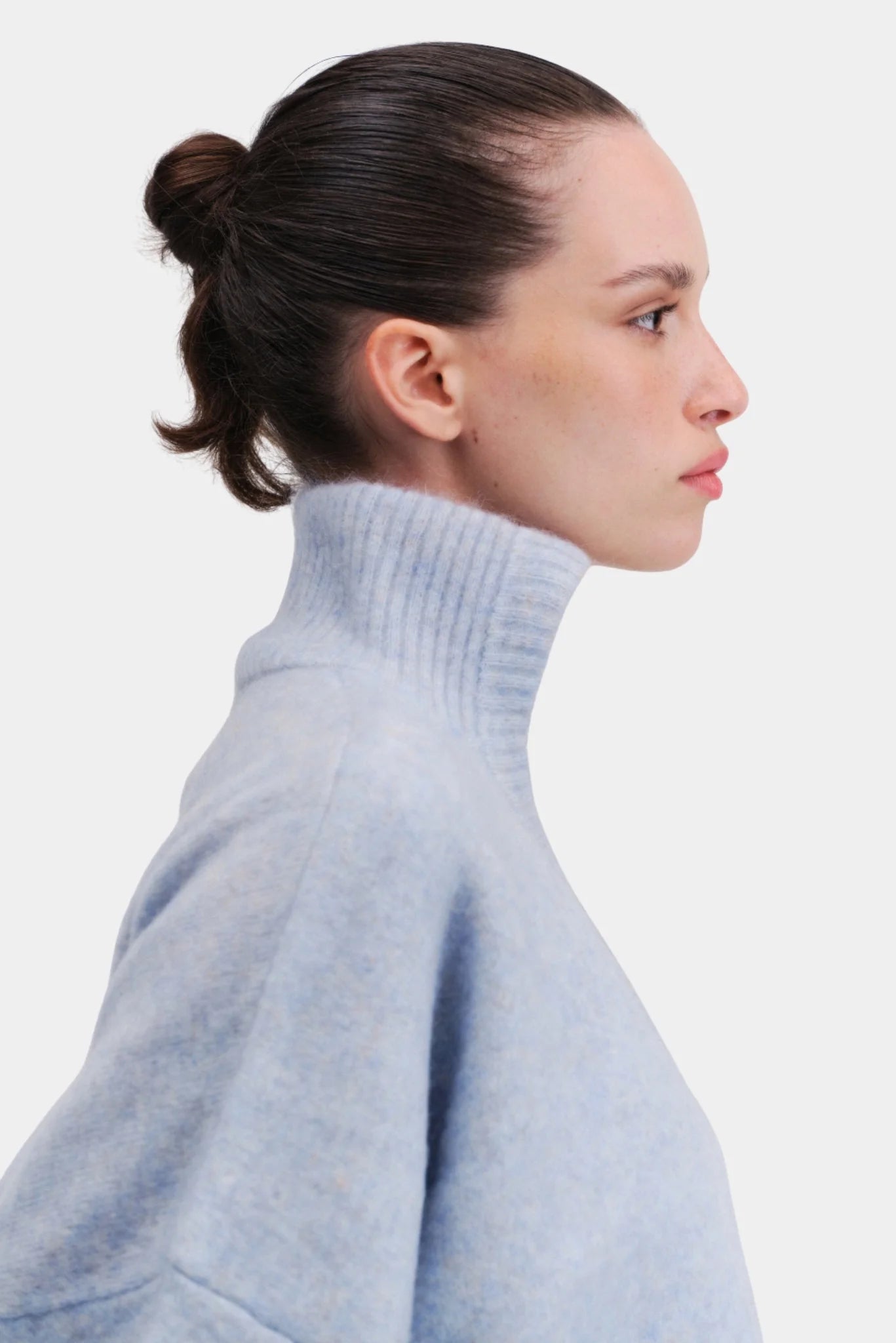 Perfil do pullover oversized em tricot azul claro com gola alta estruturada