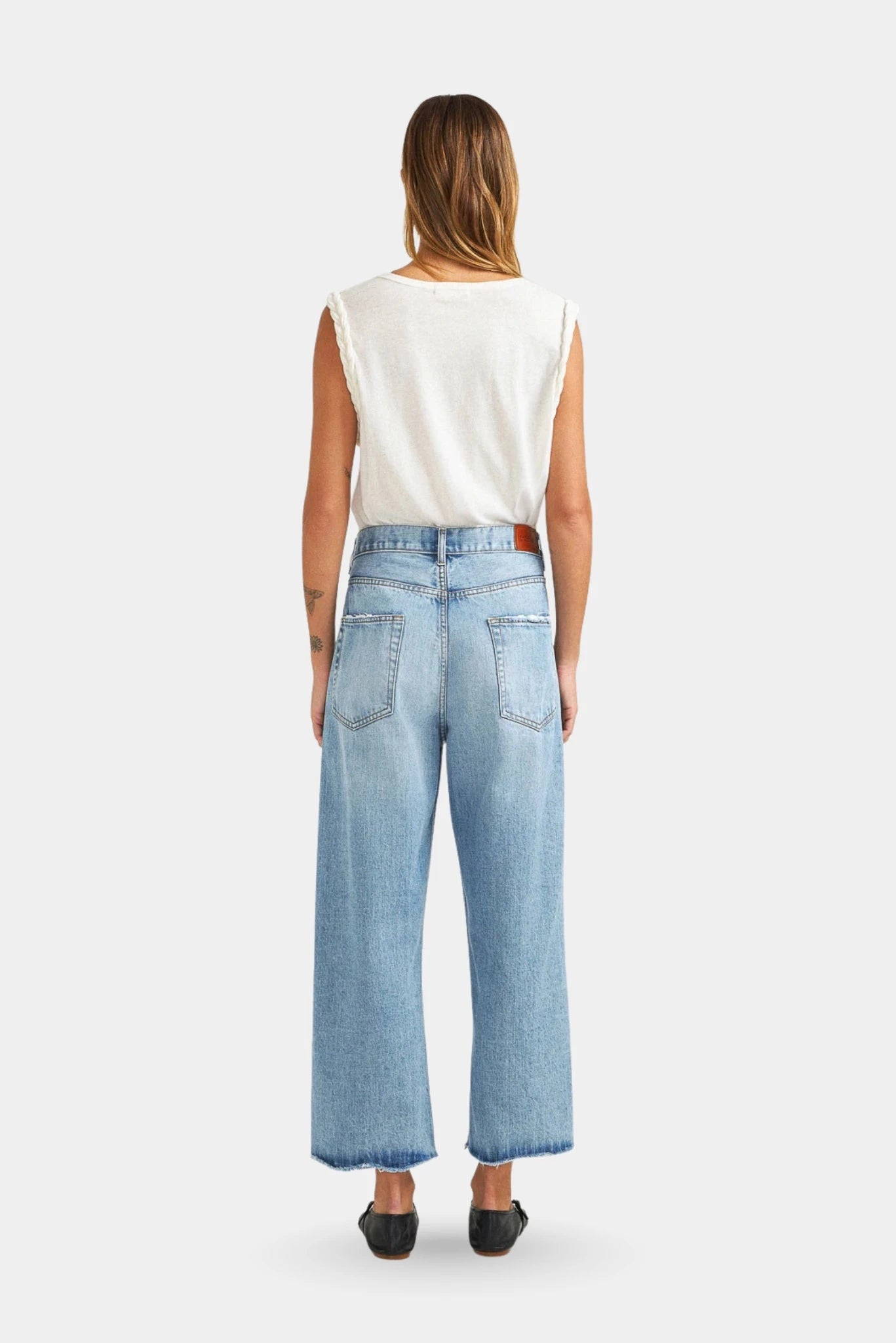 Vista traseira de calça jeans azul clara cropped com modelagem ampla