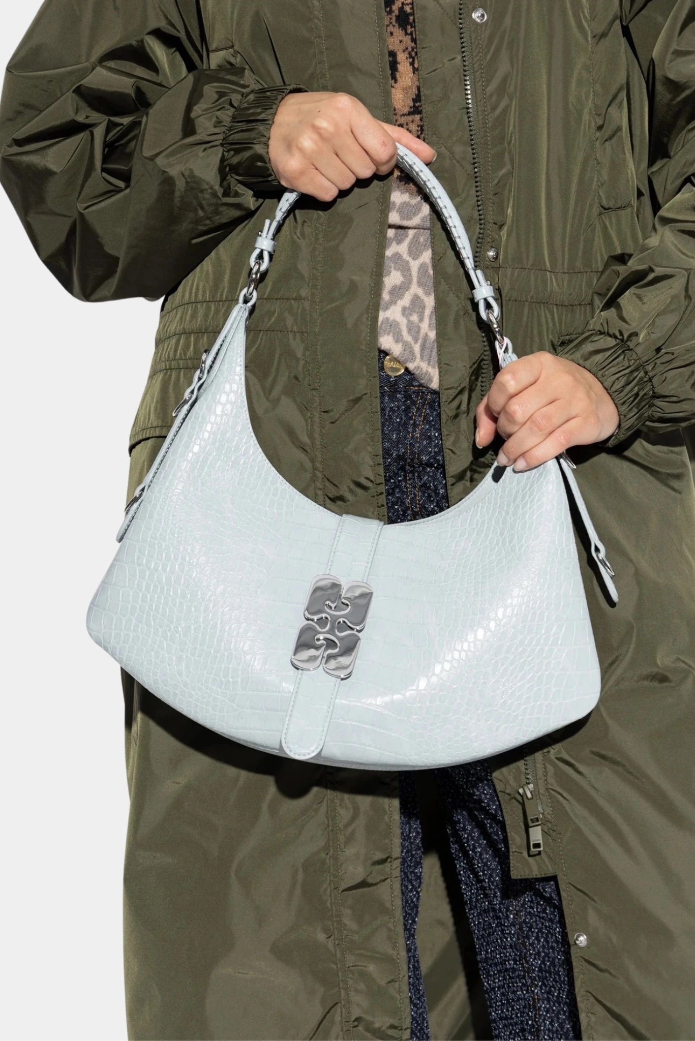 Modelo segurando bolsa Kat pequena Ganni azul-claro com textura croco