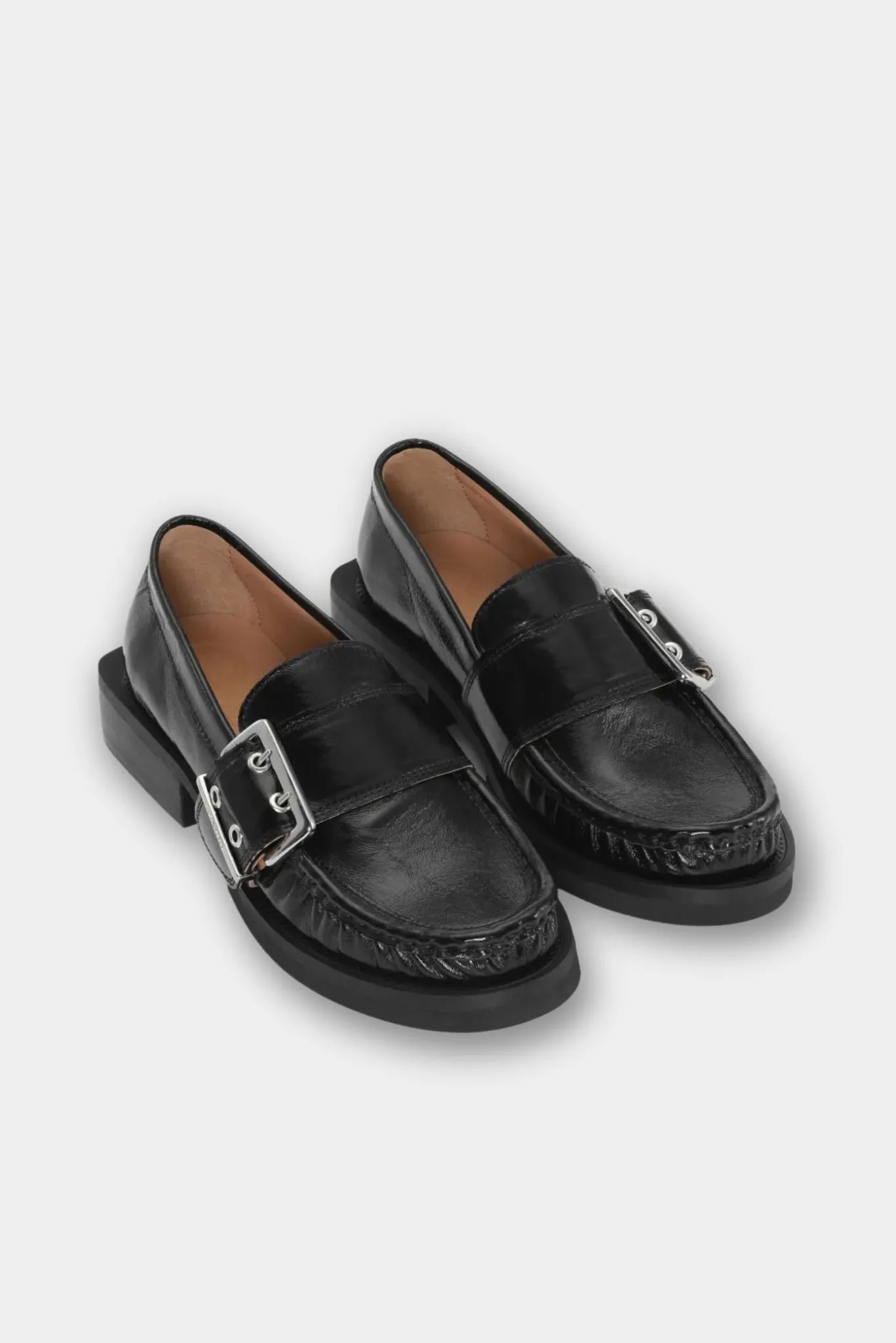 Par de mocassins Ganni pretos com fivela metálica e acabamento brilhante