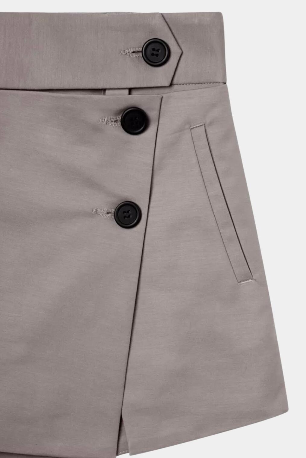 Detalhe de short saia cinza claro com botões frontais e bolso lateral embutido