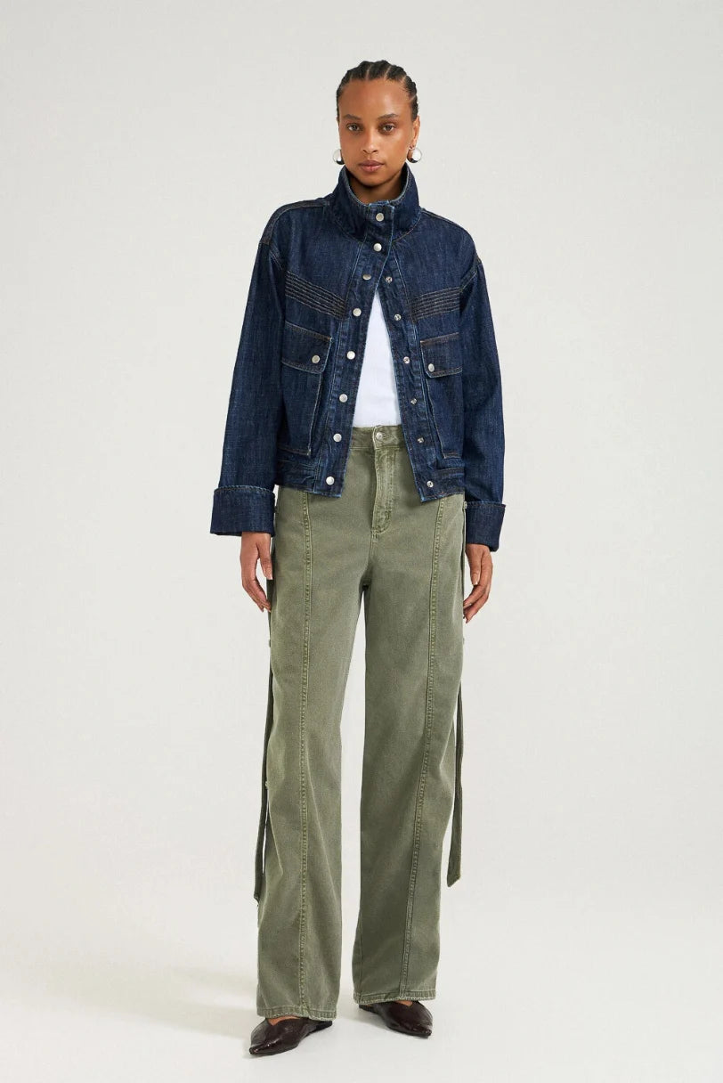 Modelo usando calça baggy verde militar LDnim com jaqueta jeans, vista frontal