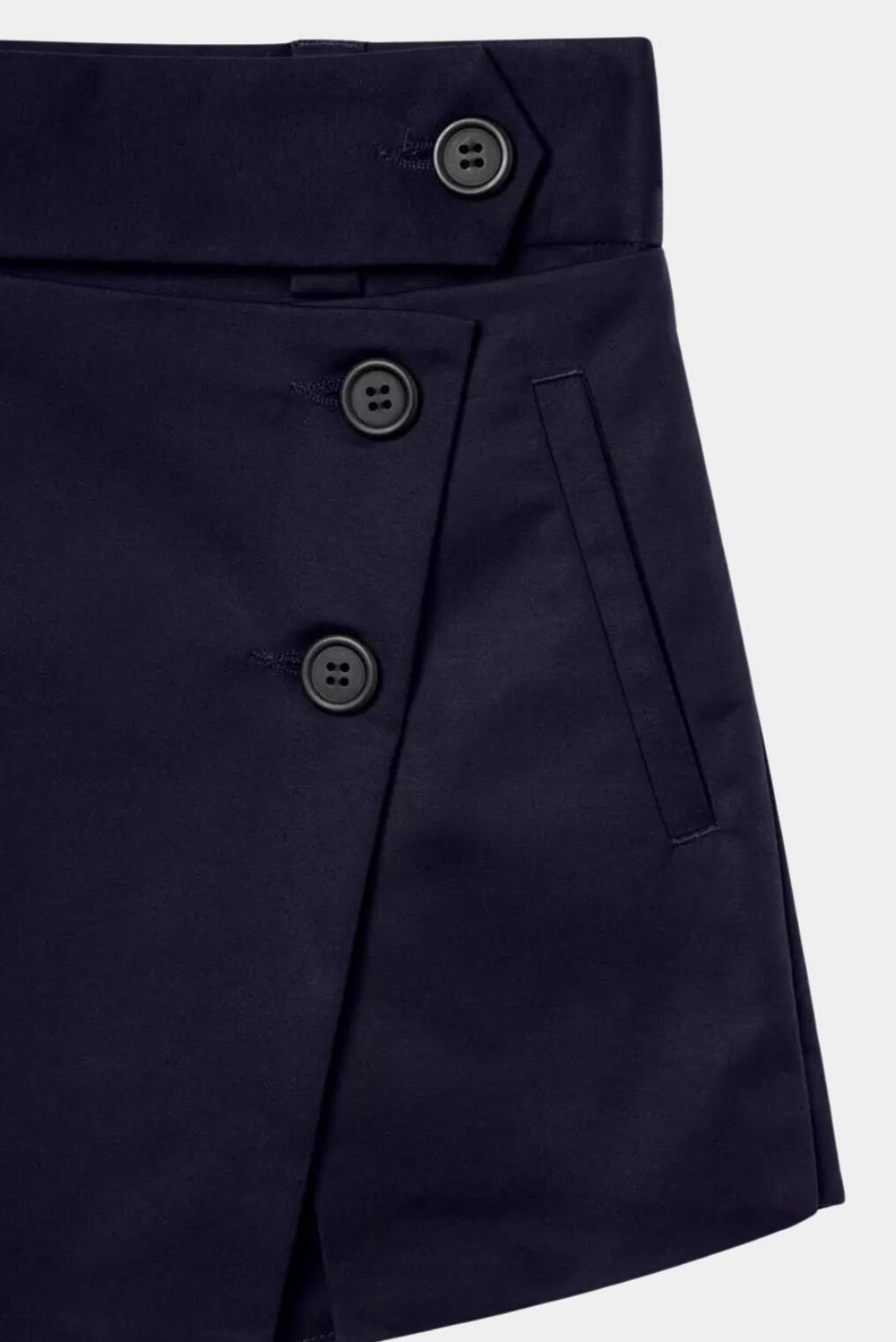 Detalhe de short saia azul-marinho com botões frontais e bolso embutido