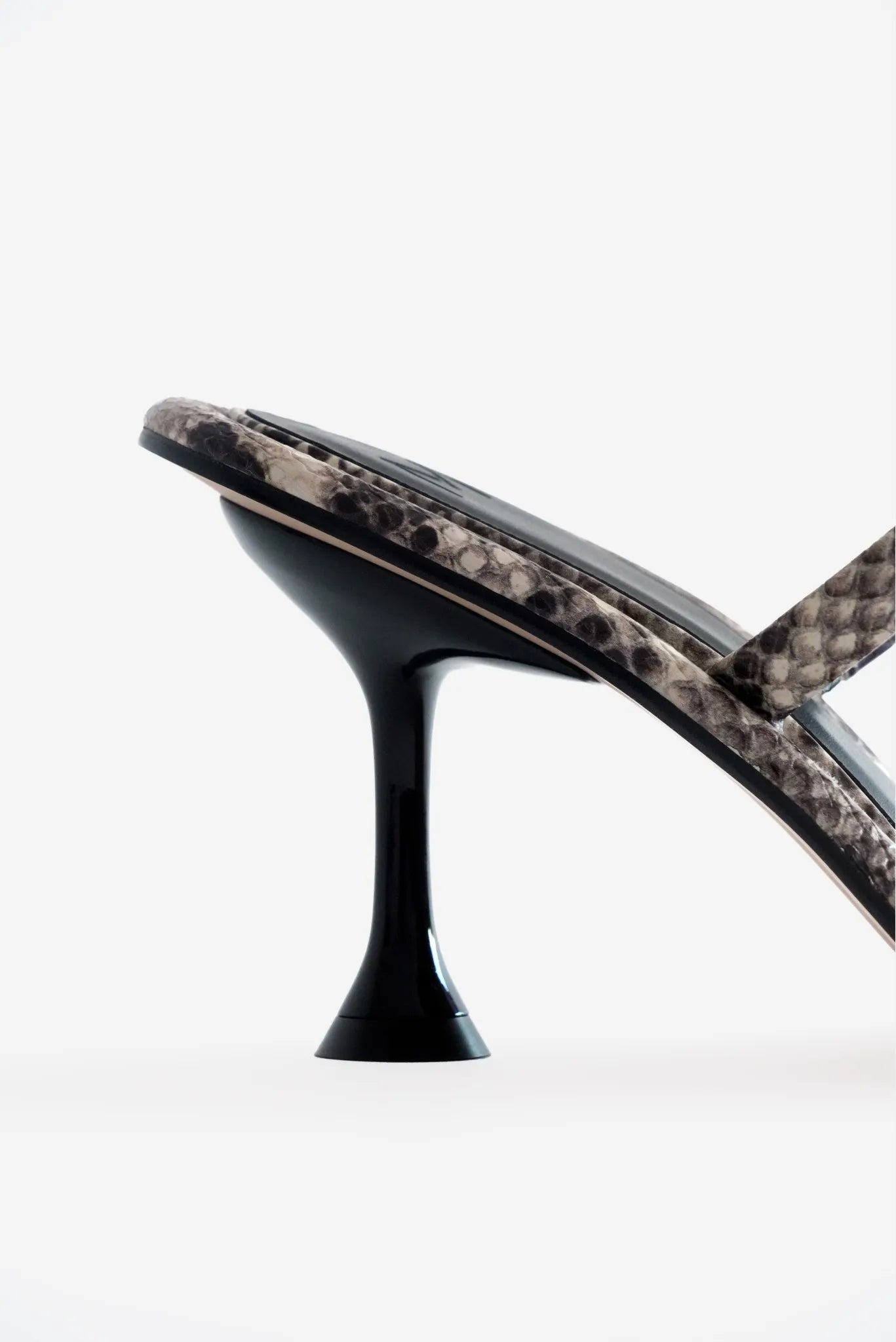Detalhe lateral da sandália com estampa python e salto preto