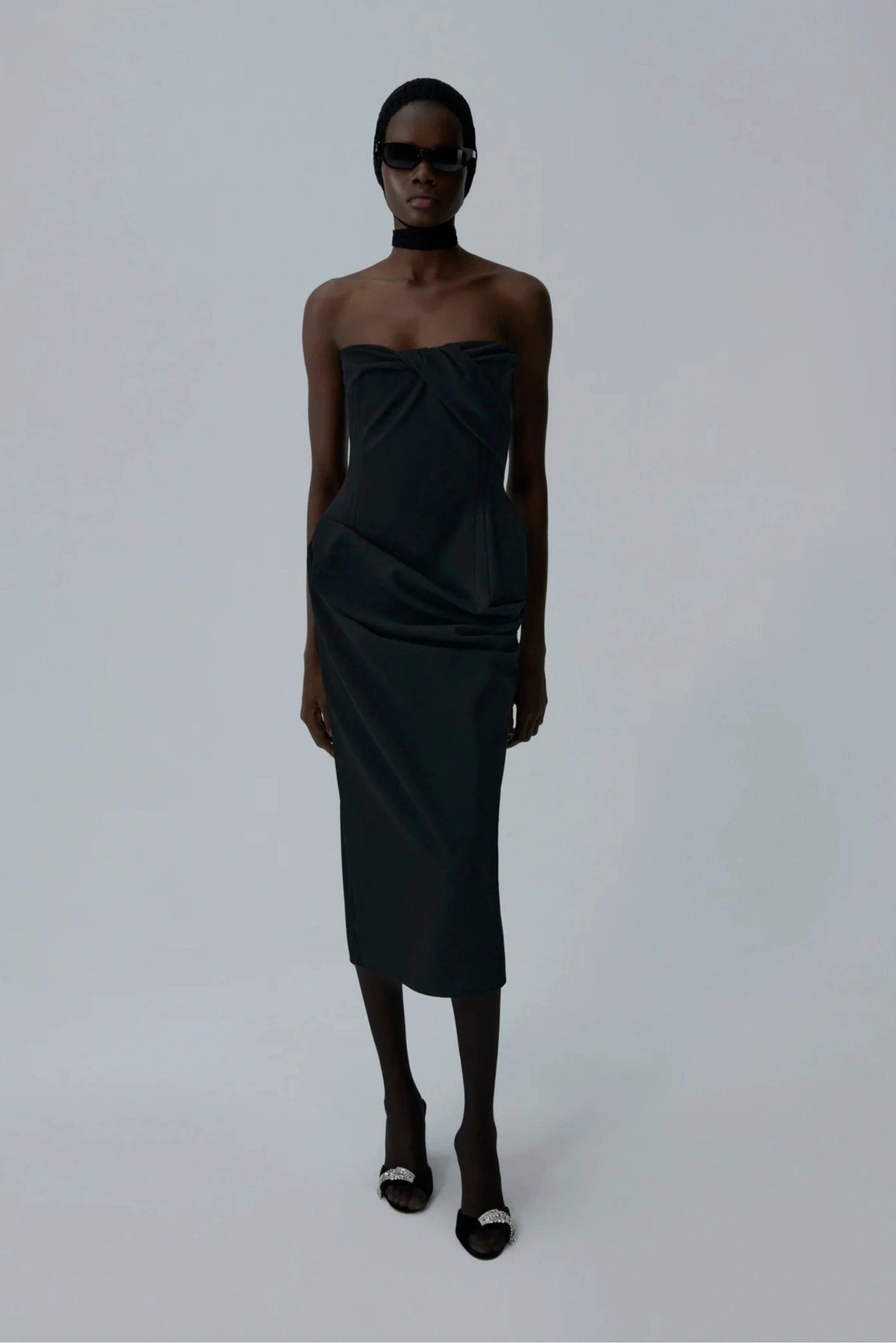 Modelo usando vestido midi preto tomara que caia com corset e drapeado lateral