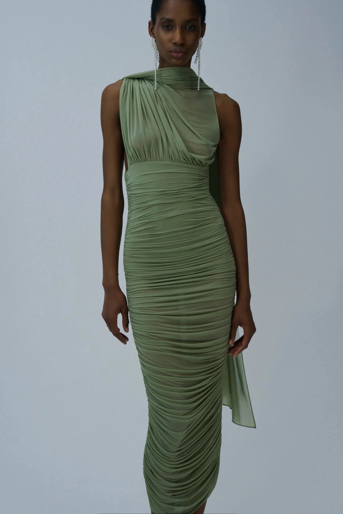 Modelo usando vestido midi verde sálvia drapeado com gola alta e caimento ajustado
