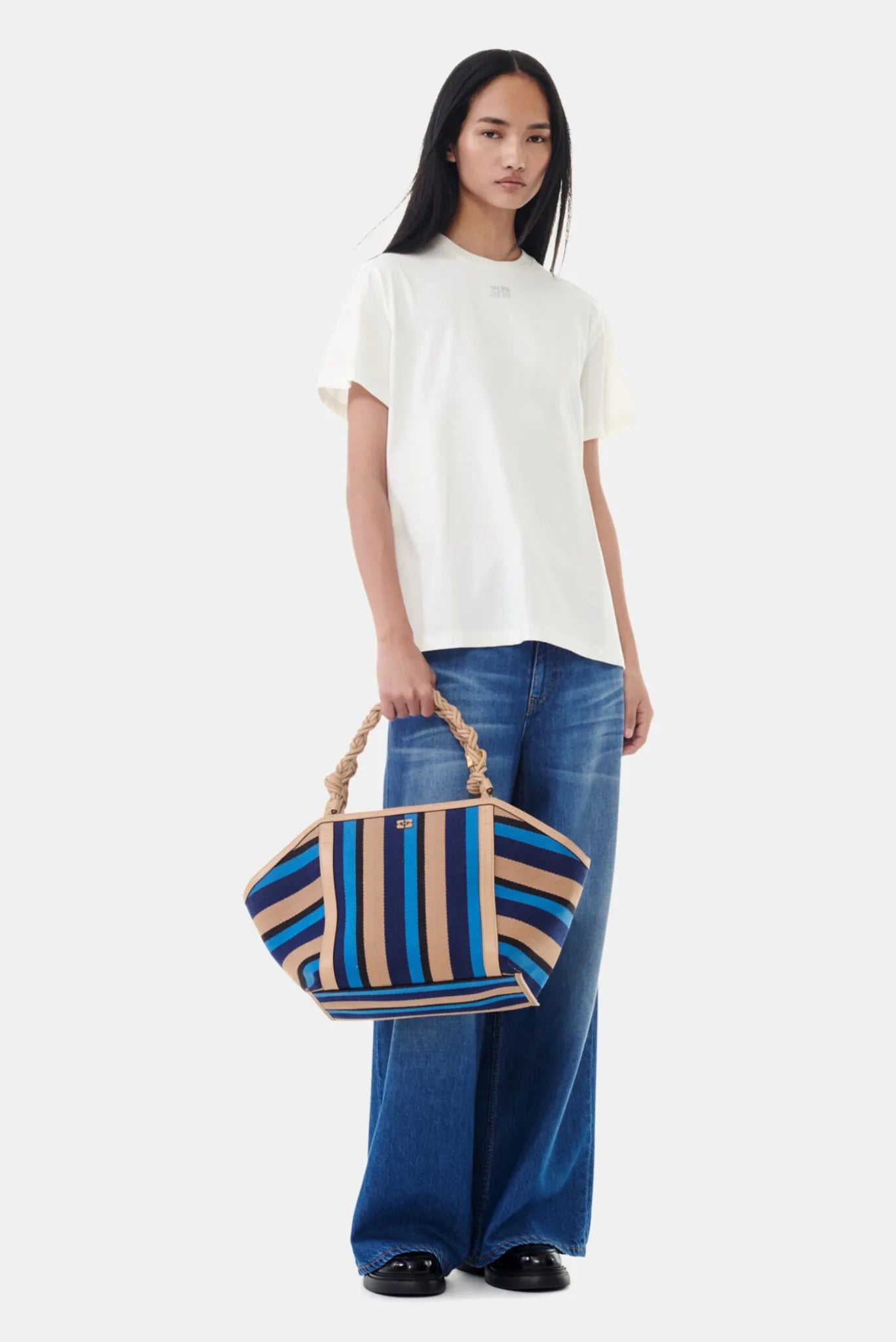 Camiseta Relaxed Ganni off-white com strass combinada com jeans amplo e bolsa listrada