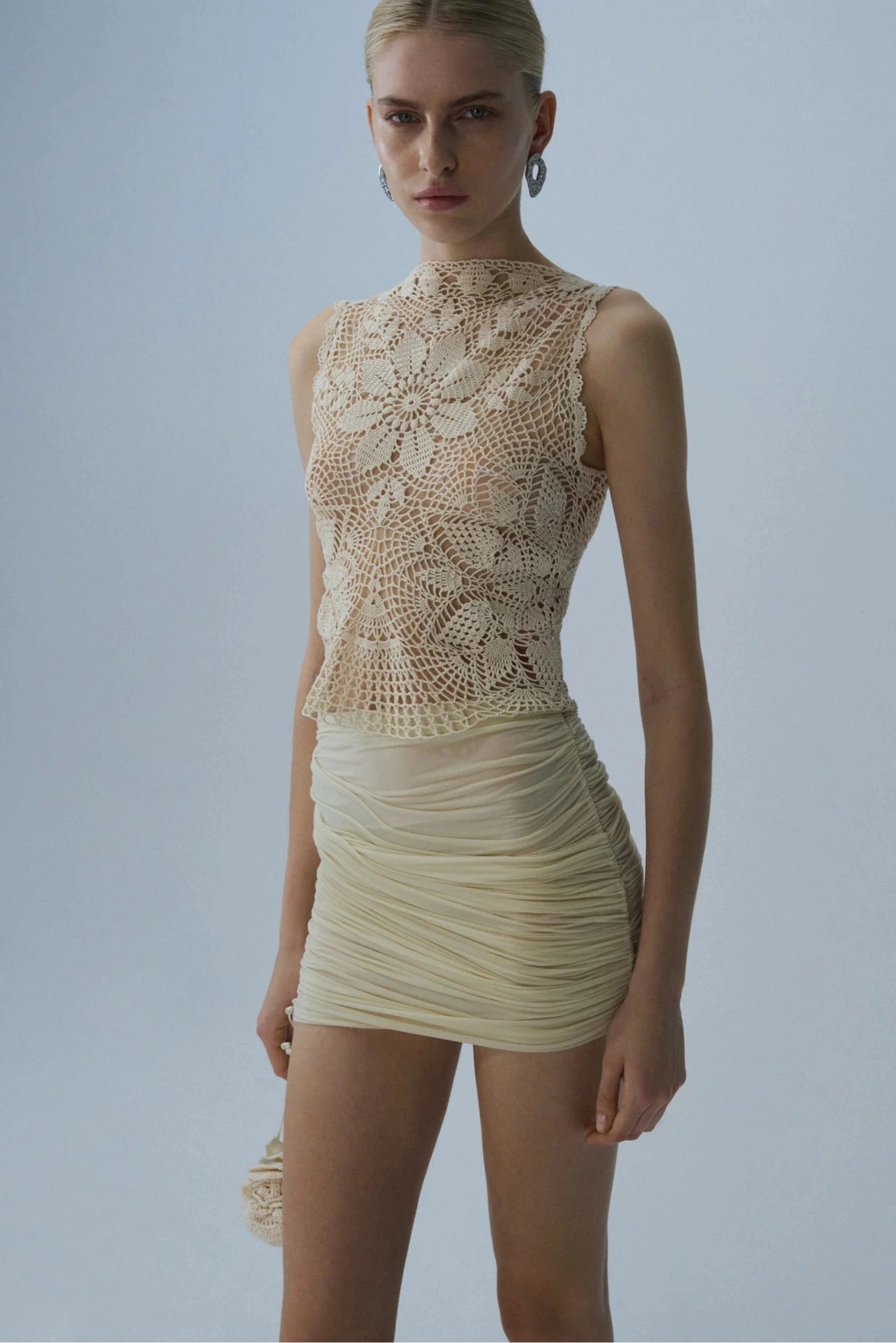 Modelo usando top de crochet bege com desenho floral e gola alta delicada
