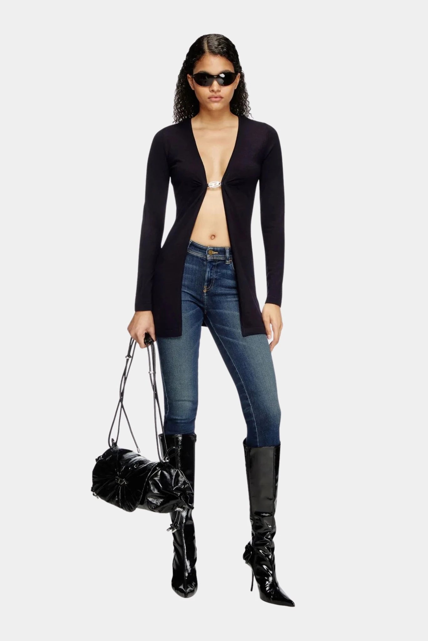 Look Diesel com suéter preto decotado, jeans skinny e botas de cano alto