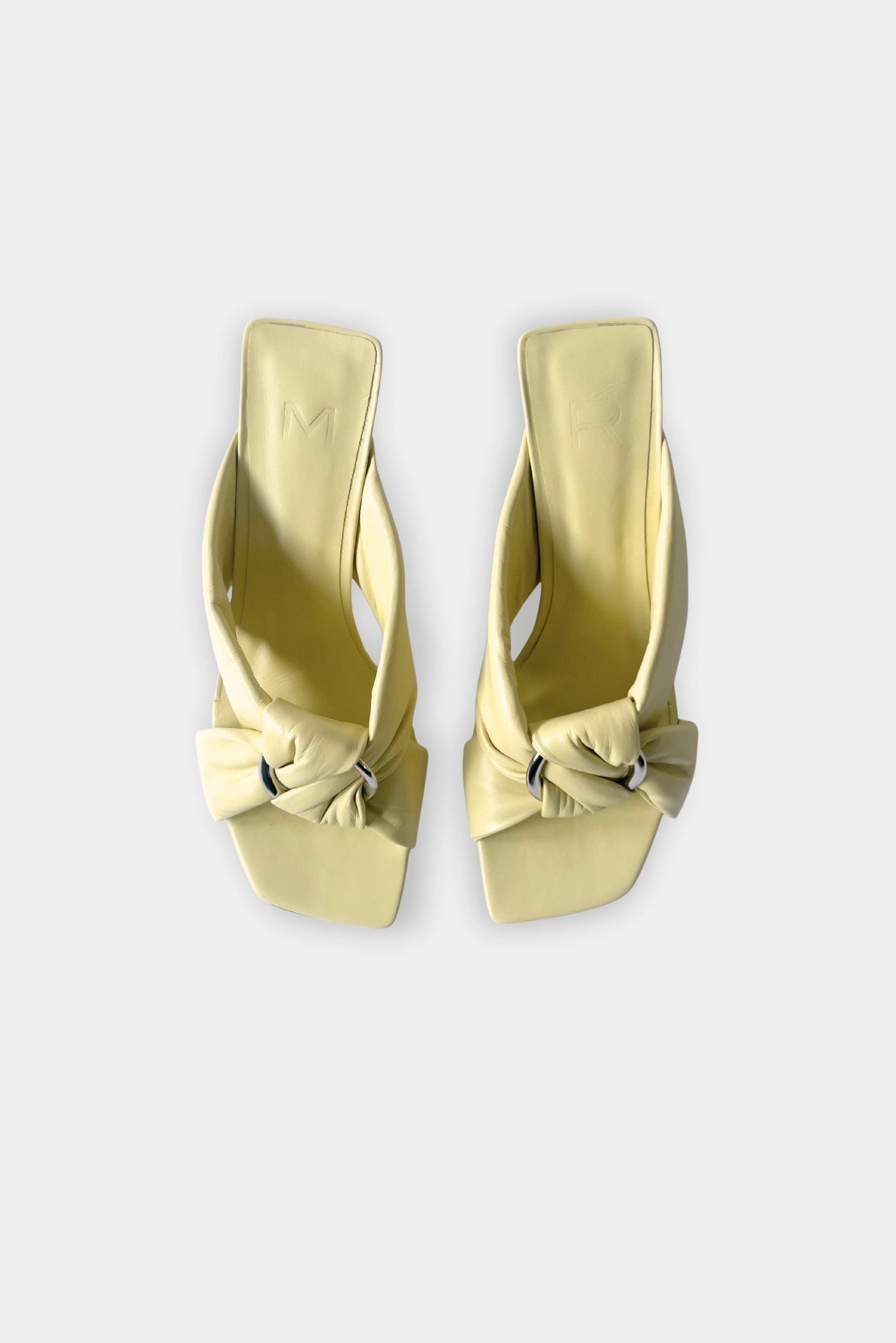 Sandália mule amarelo claro com nó frontal e detalhe metálico vista superior
