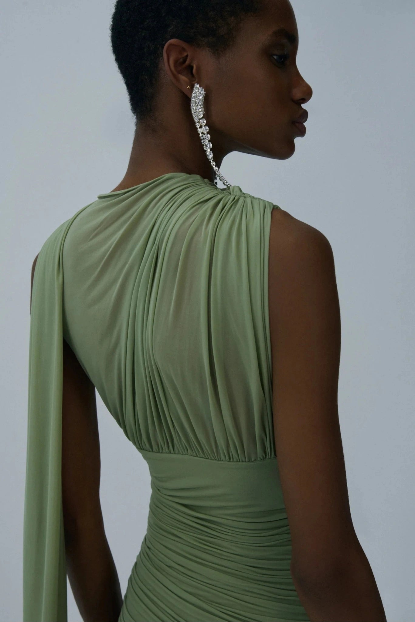 Detalhe das costas de vestido verde sálvia drapeado com painel fluido e gola alta