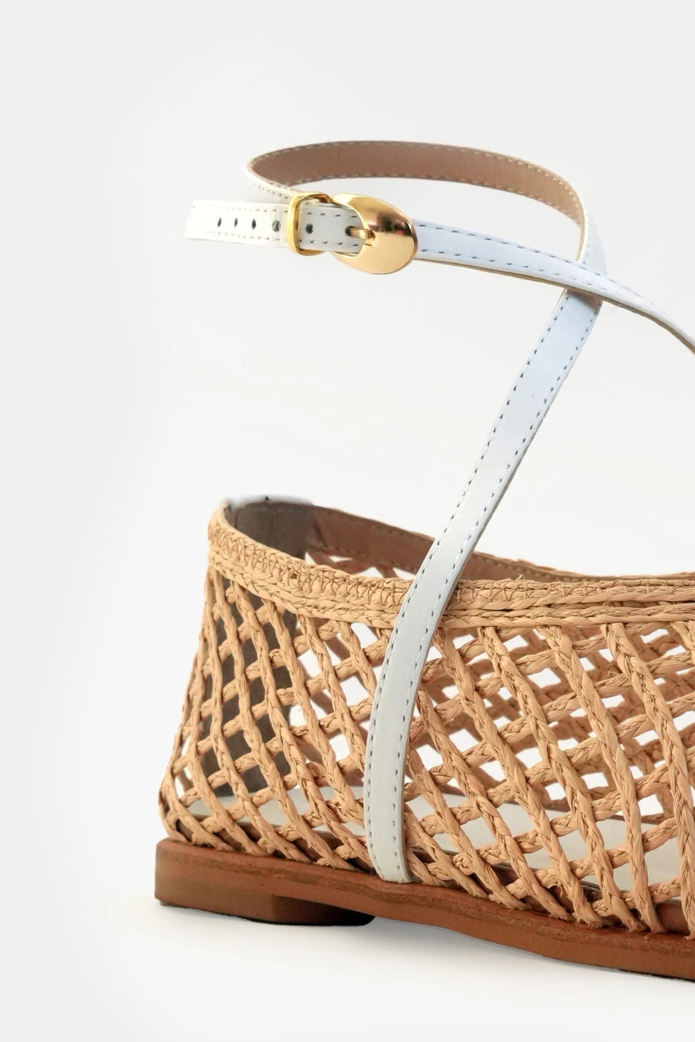 Detalhe da tira off white com fivela dourada em sapatilha trançada natural