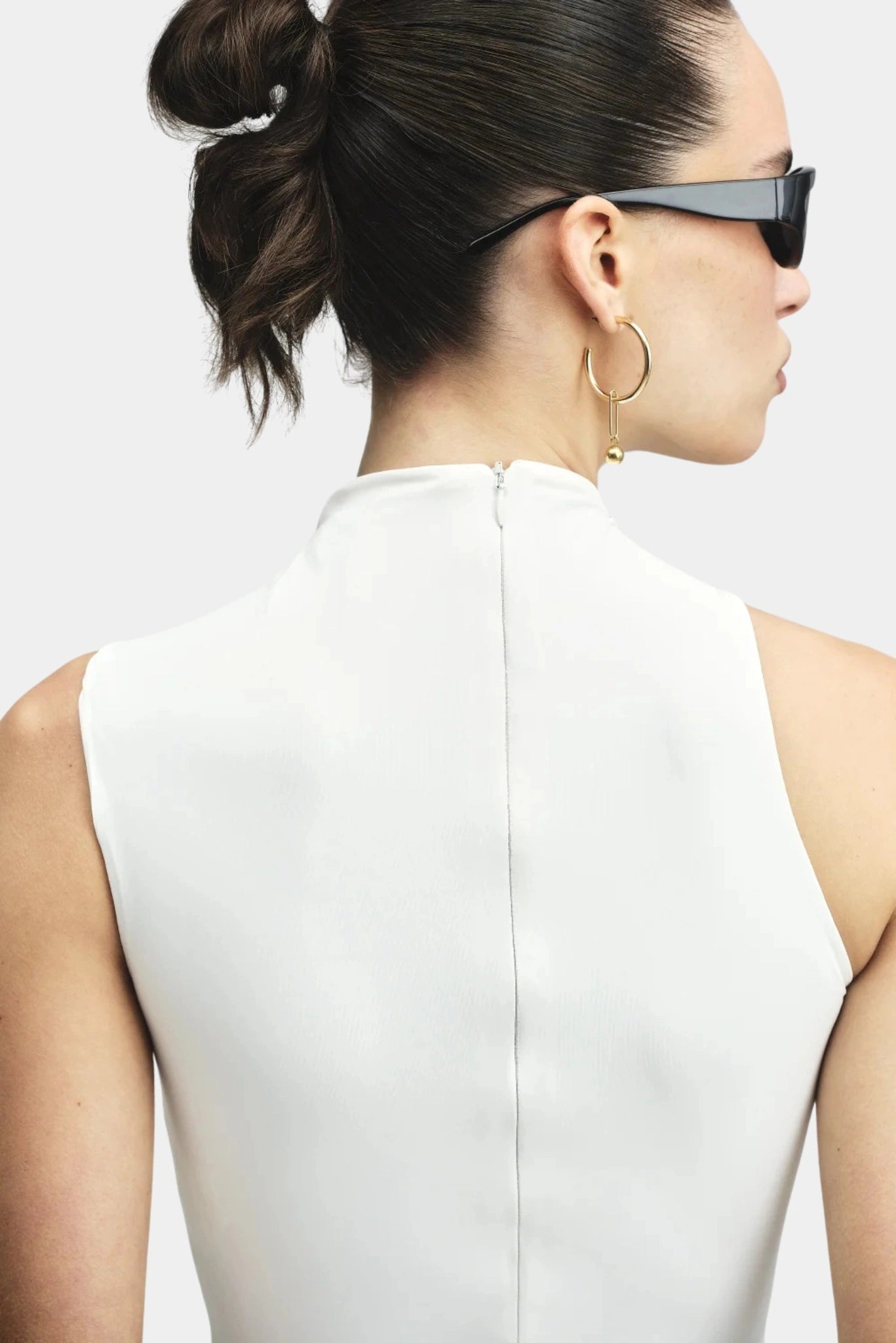 Costas da blusa branca sem mangas com fechamento posterior discreto