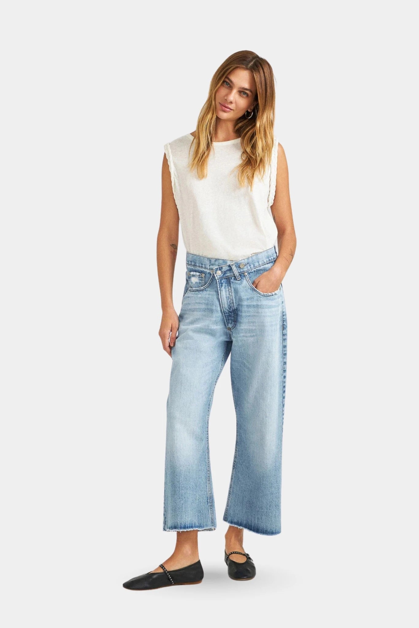 Modelo usando calça jeans azul clara com cós transpassado e barra cropped