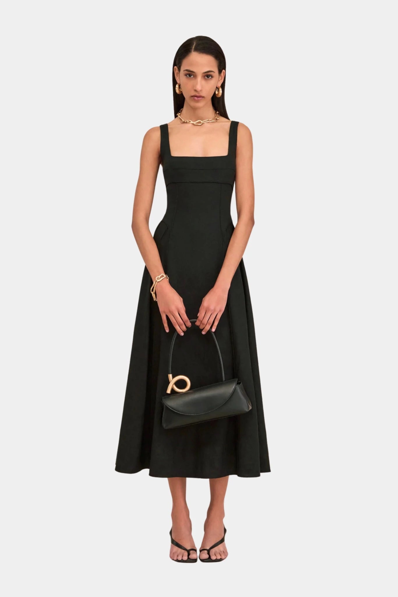 Modelo com bolsa preta Cult Gaia de alça rígida e detalhe dourado