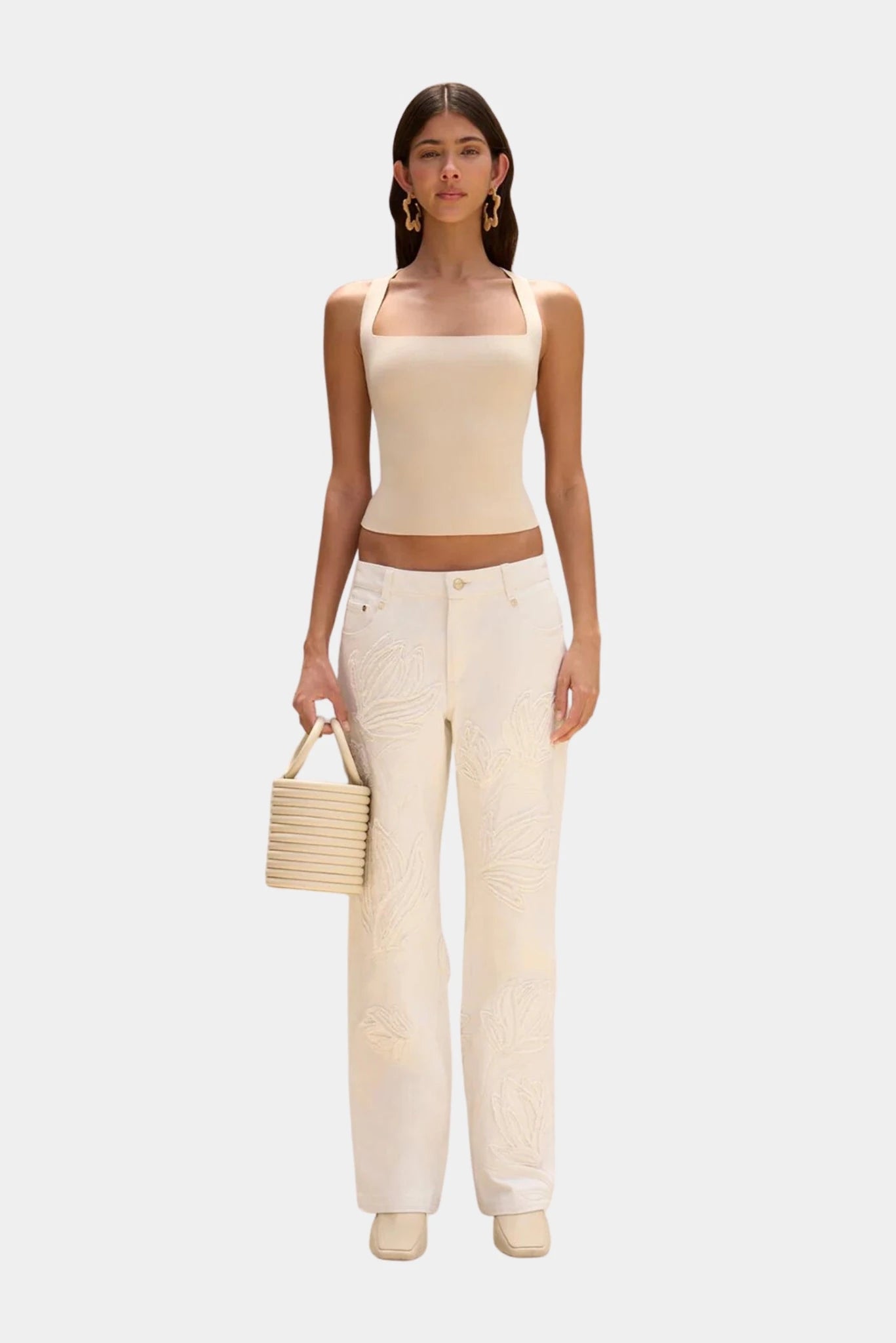 Modelo com bolsa Yasmina Cult Gaia bege e conjunto off-white minimalista
