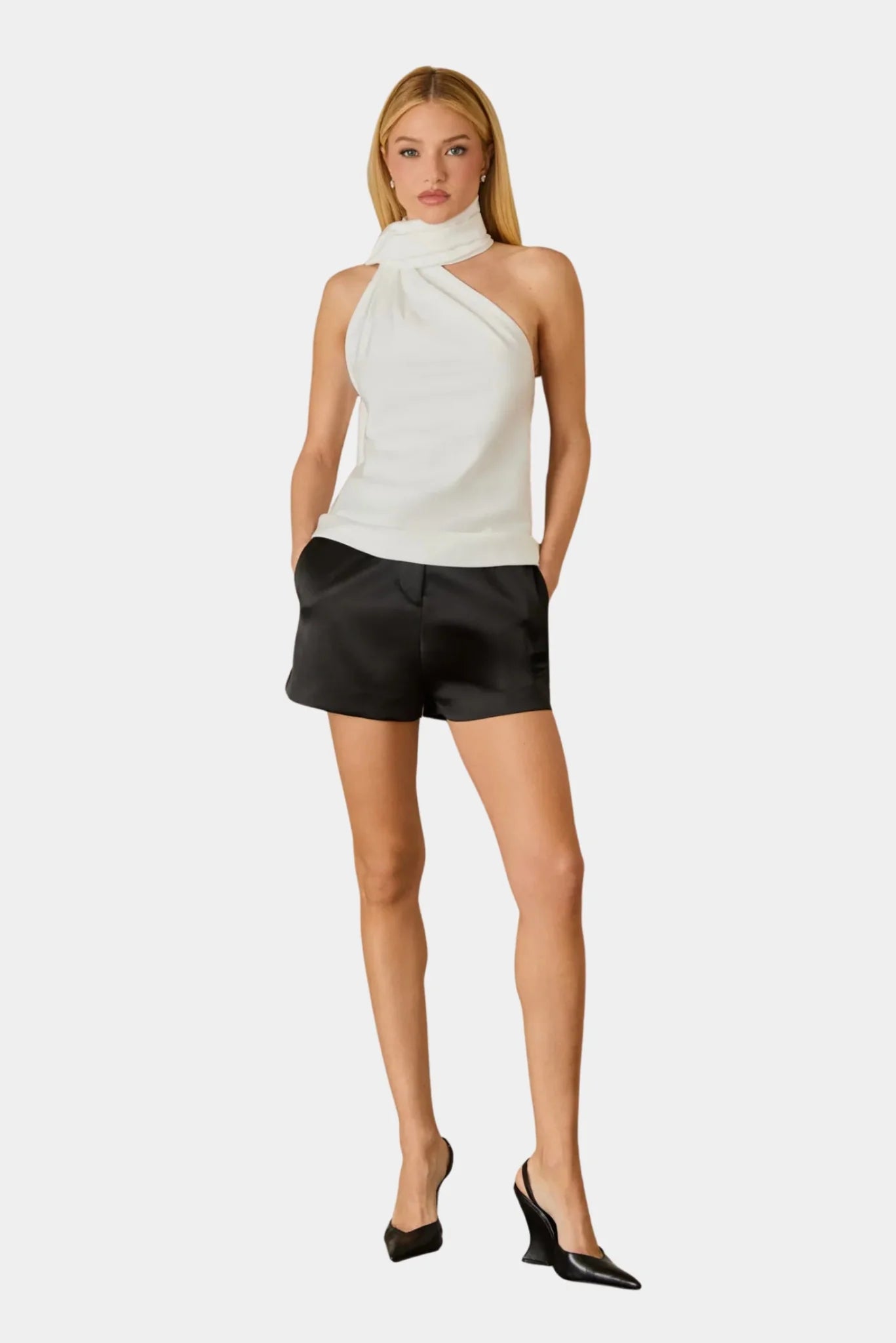 Blusa Nay off white em cetim com gola alta drapeada e faixa longa, combinada com shorts preto