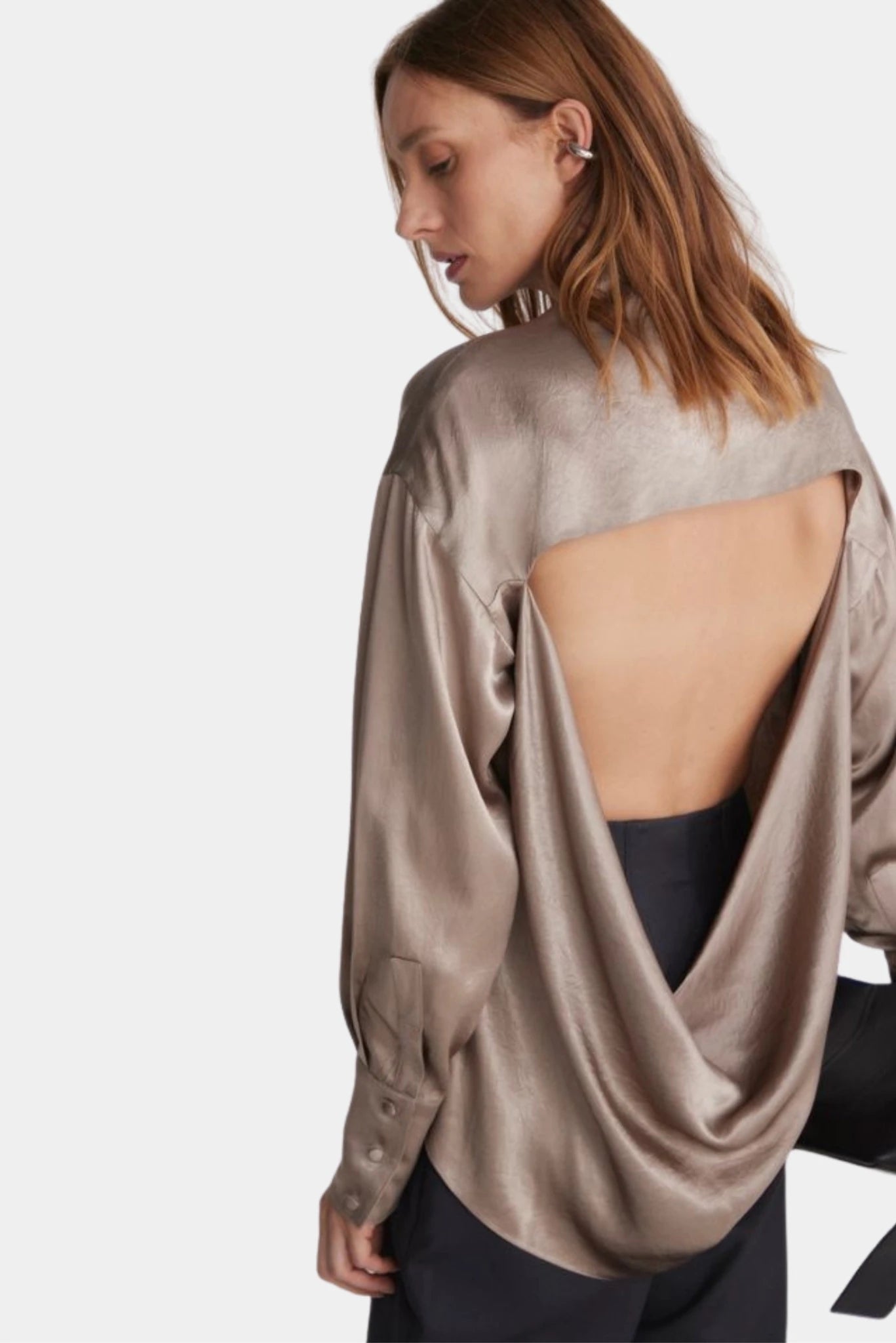 Costas da blusa bege acetinada com decote profundo e efeito drapeado