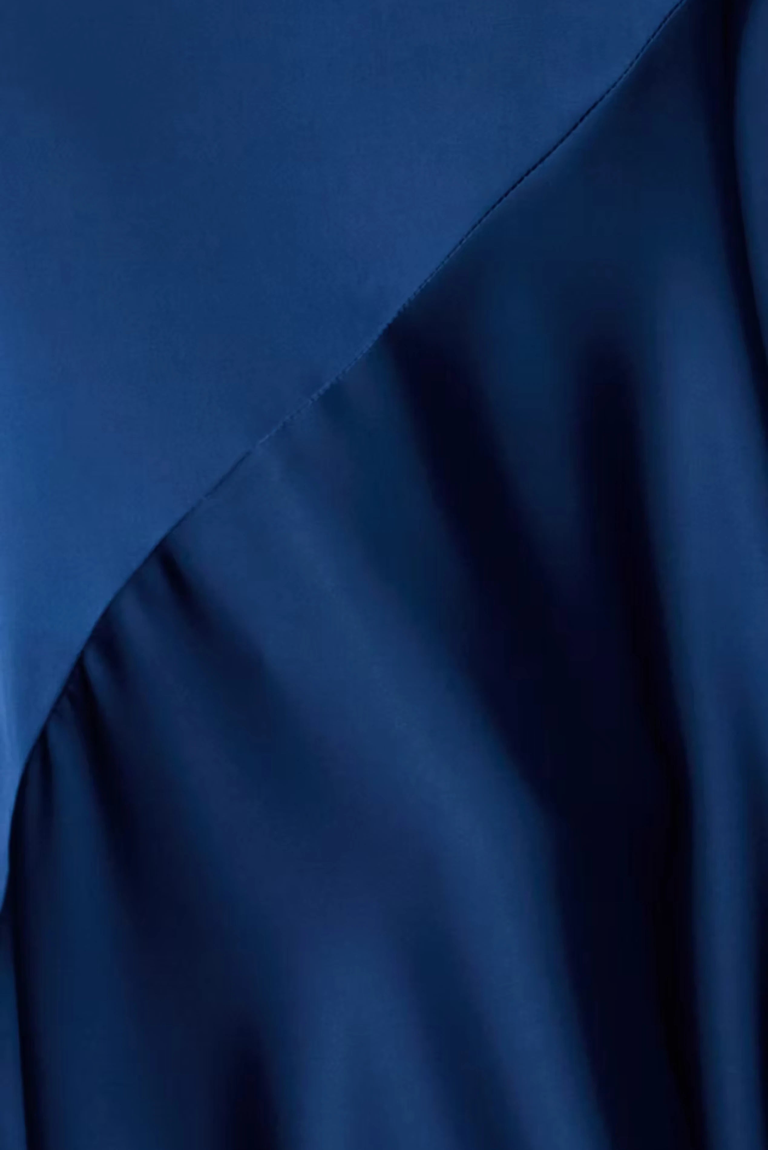 Detalhe do vestido longo azul-marinho com recorte diagonal e acabamento acetinado