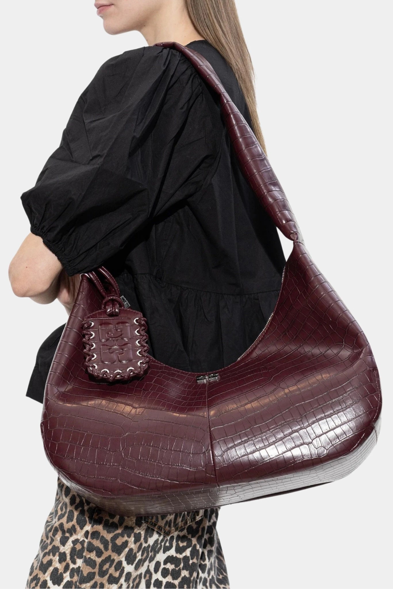 Modelo usando bolsa hobo Ganni vinho com textura croco e alça larga