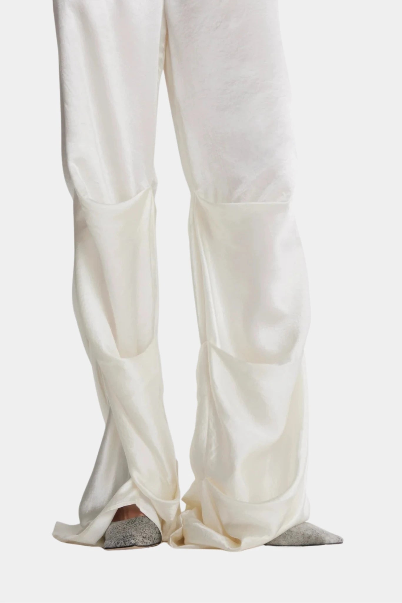 Detalhe da calça off-white com recortes volumosos e modelagem ampla