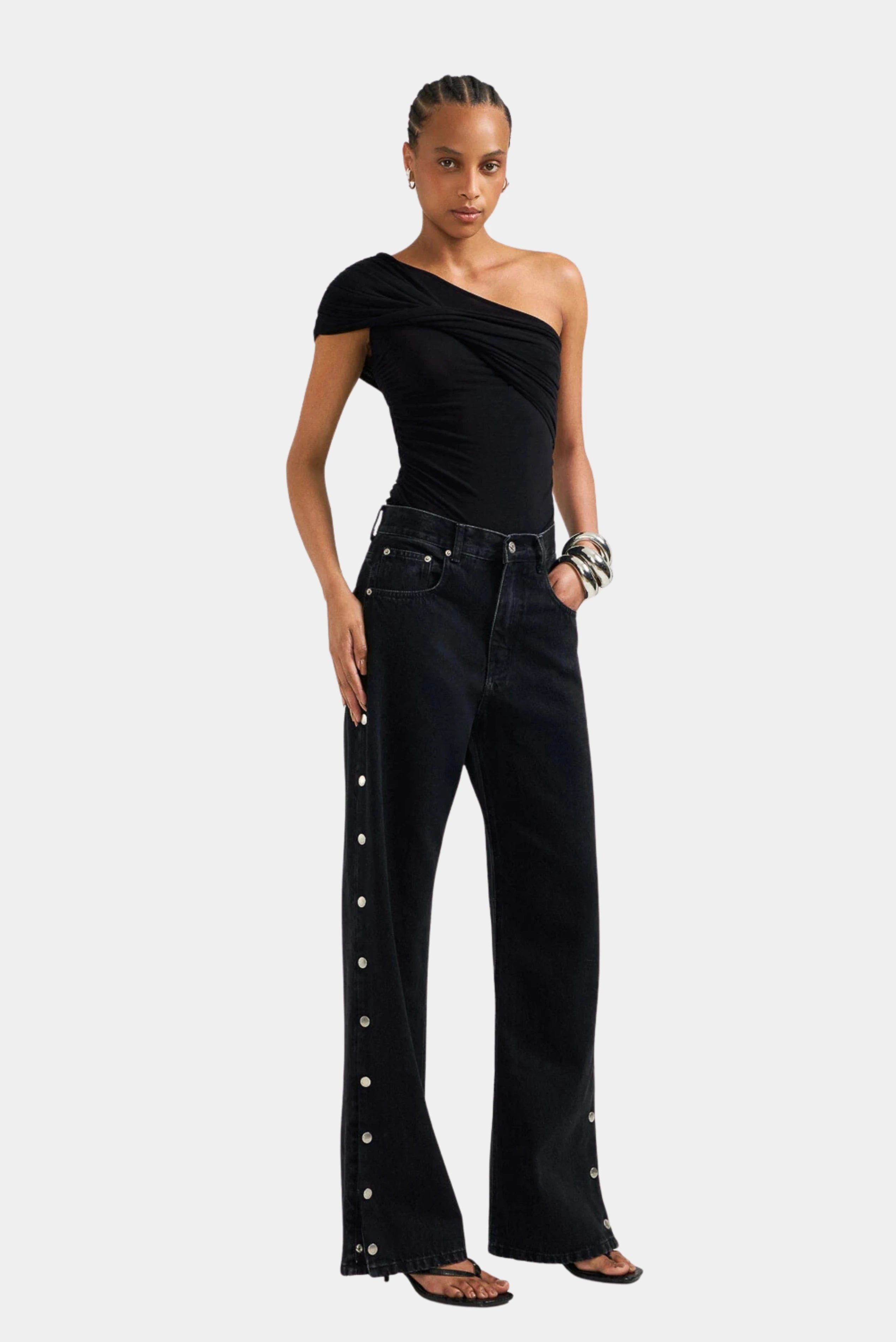 Calça jeans preta loose de cintura alta com botões metálicos laterais, vestida pela modelo LDnim